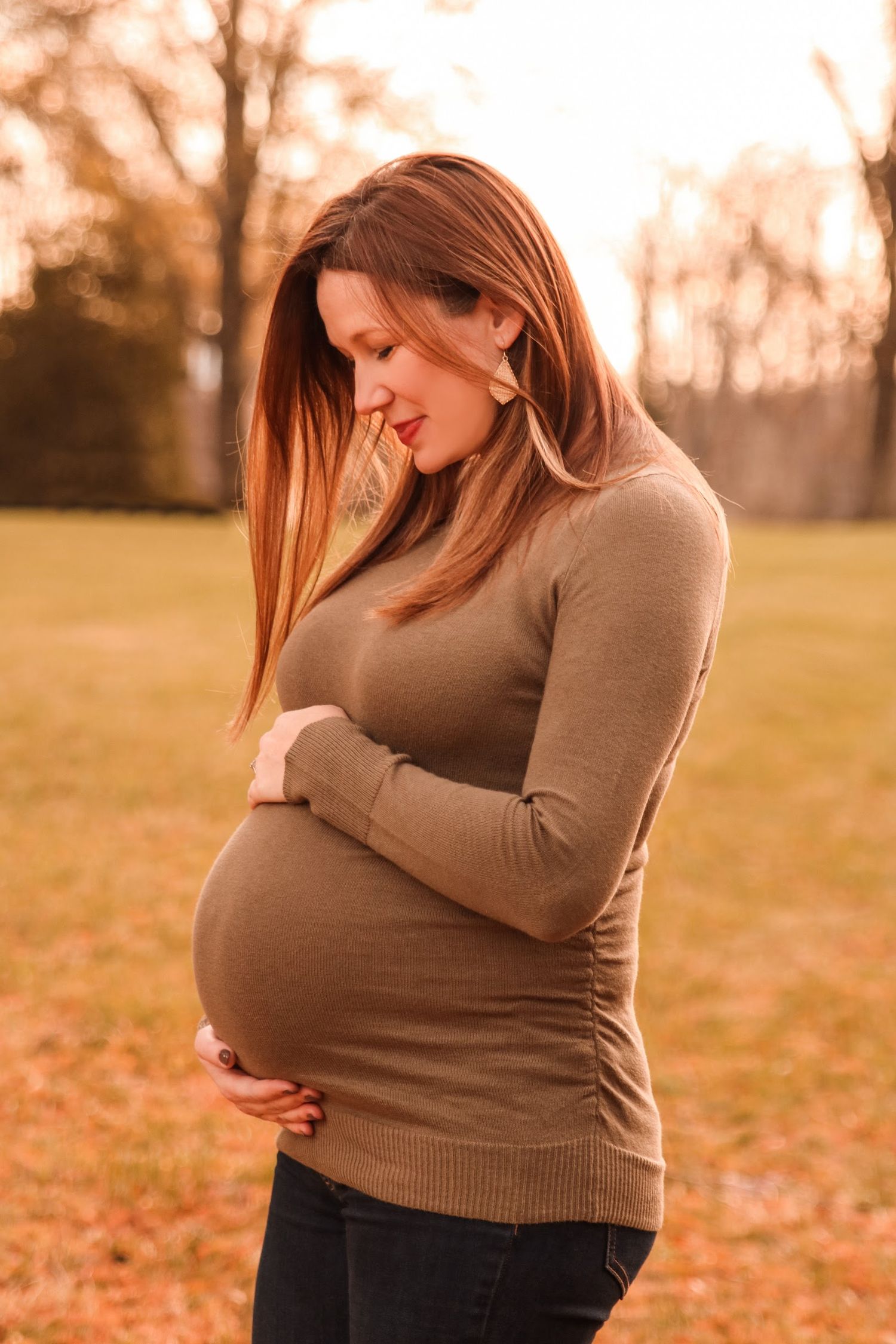 Maternity photos in autumn setting with warm sunset lighting.