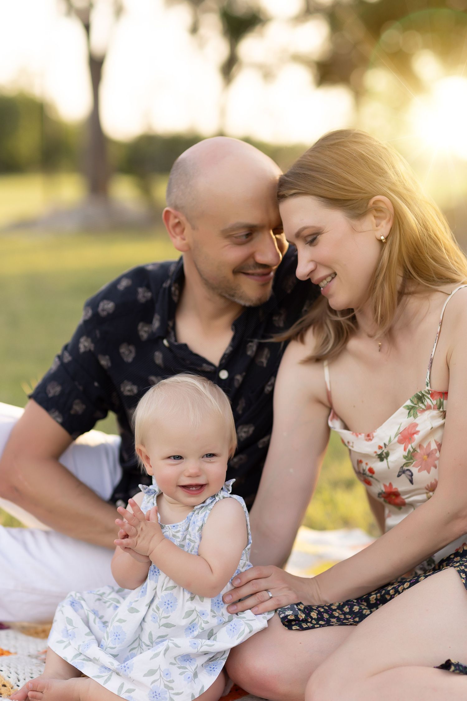 A family enjoys tender moments together in golden sunset light at a park.