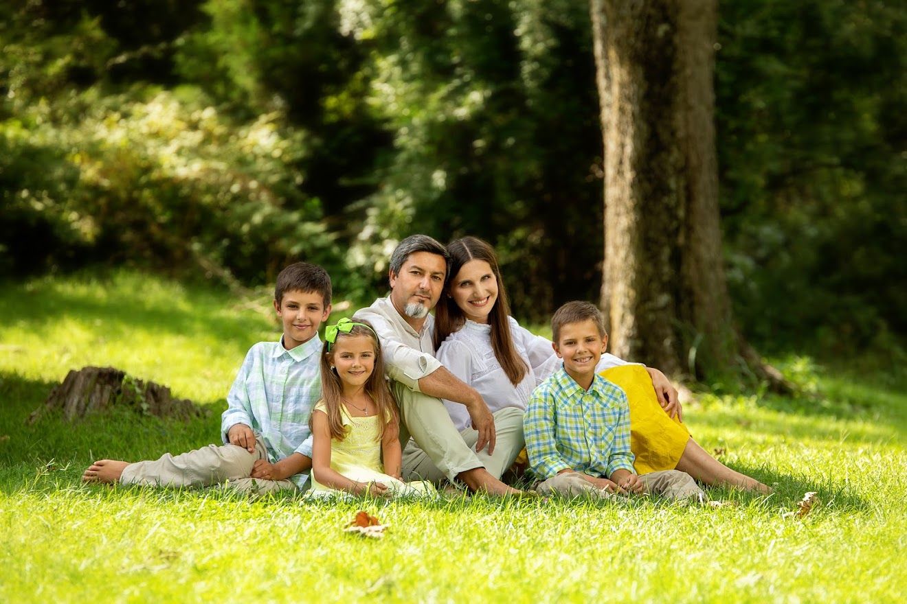 A group poses together while lying on grass in a wooded setting.
