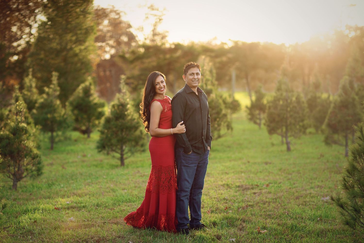 Couple walking through a sunlit field at golden hour holding hands.