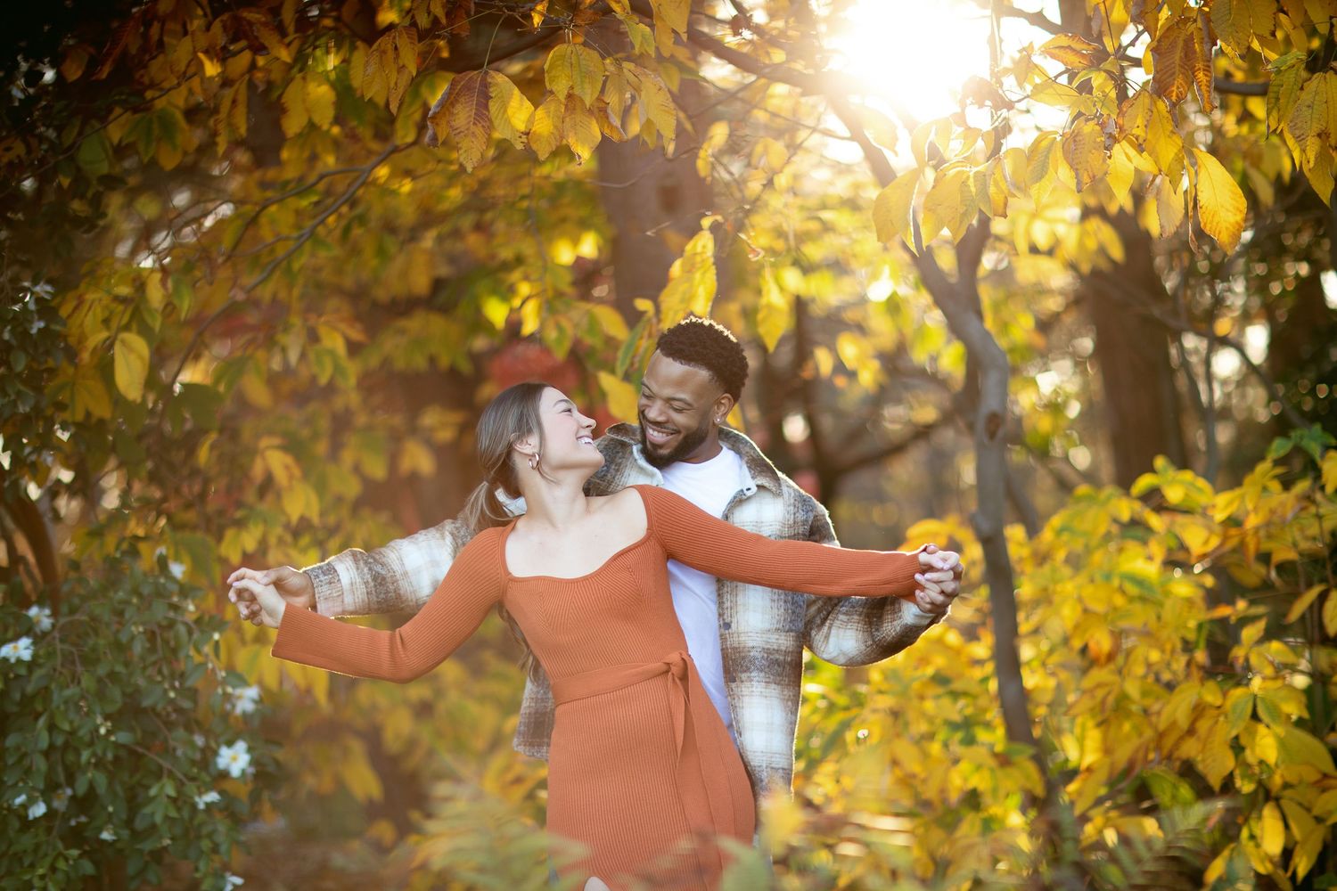 Autumn family photoshoot among golden leaves and sunlit trees.