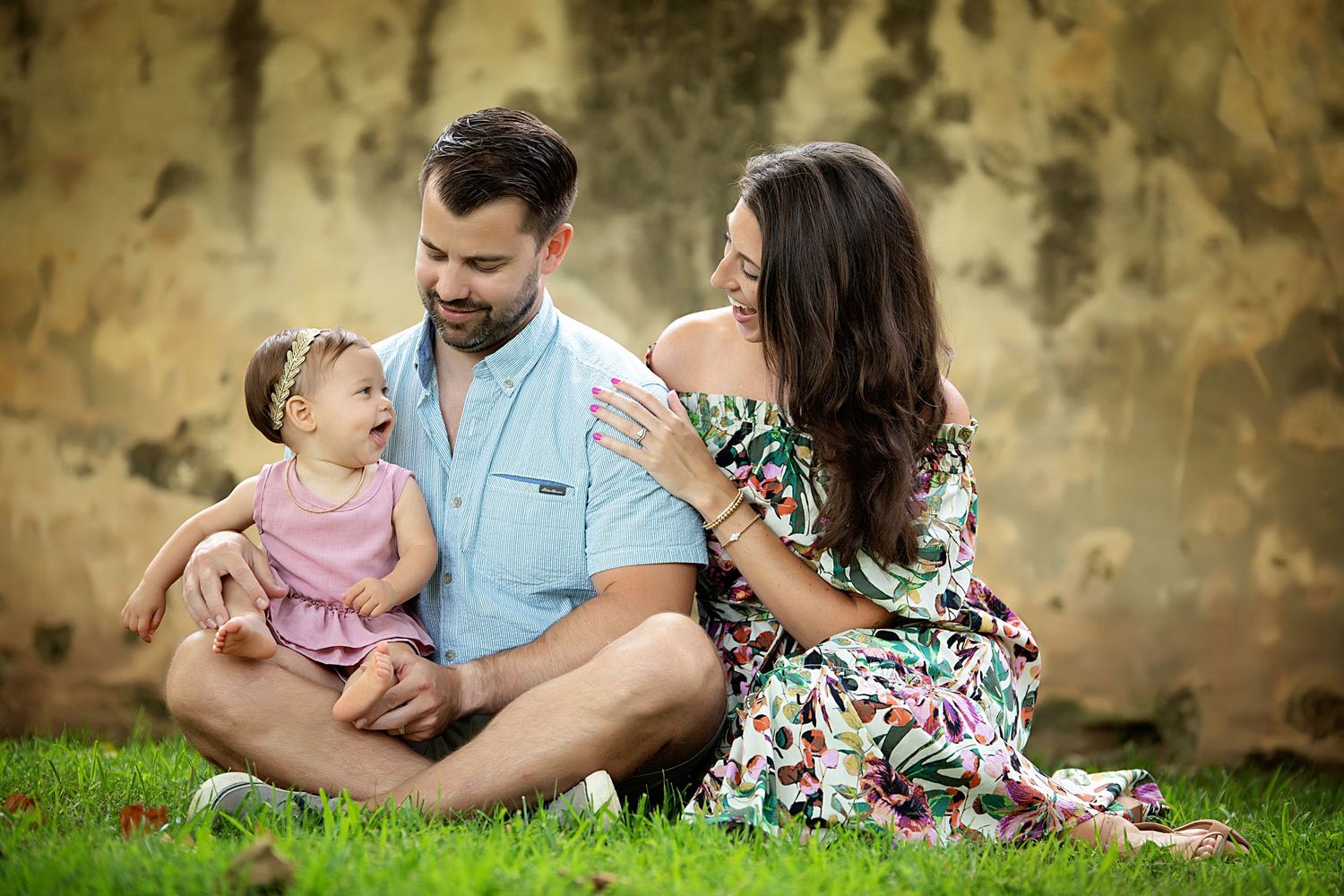 Family relaxing together on grass during golden hour outdoor photo session.