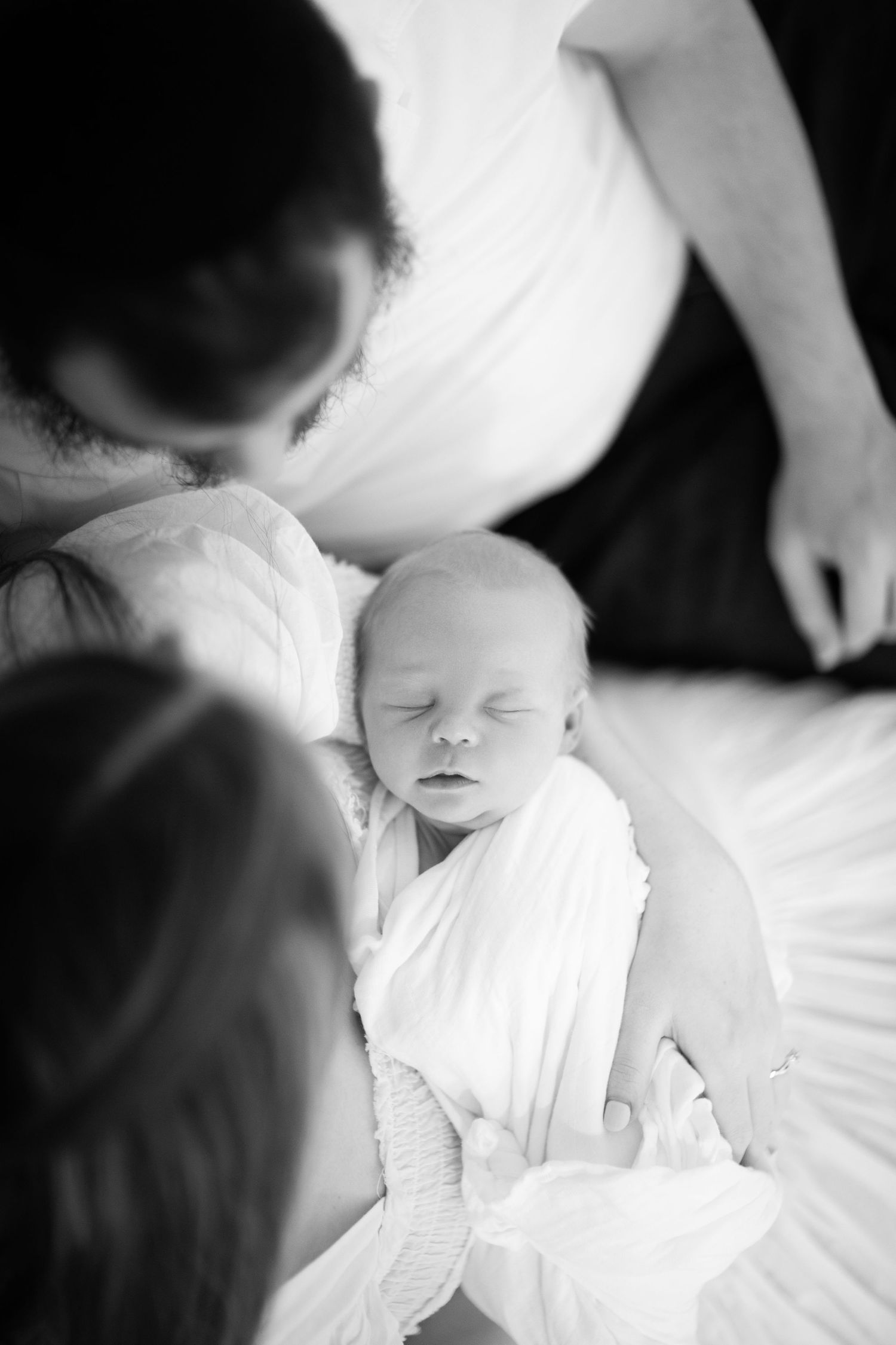 Black and white portrait of peaceful newborn in soft white fabric.