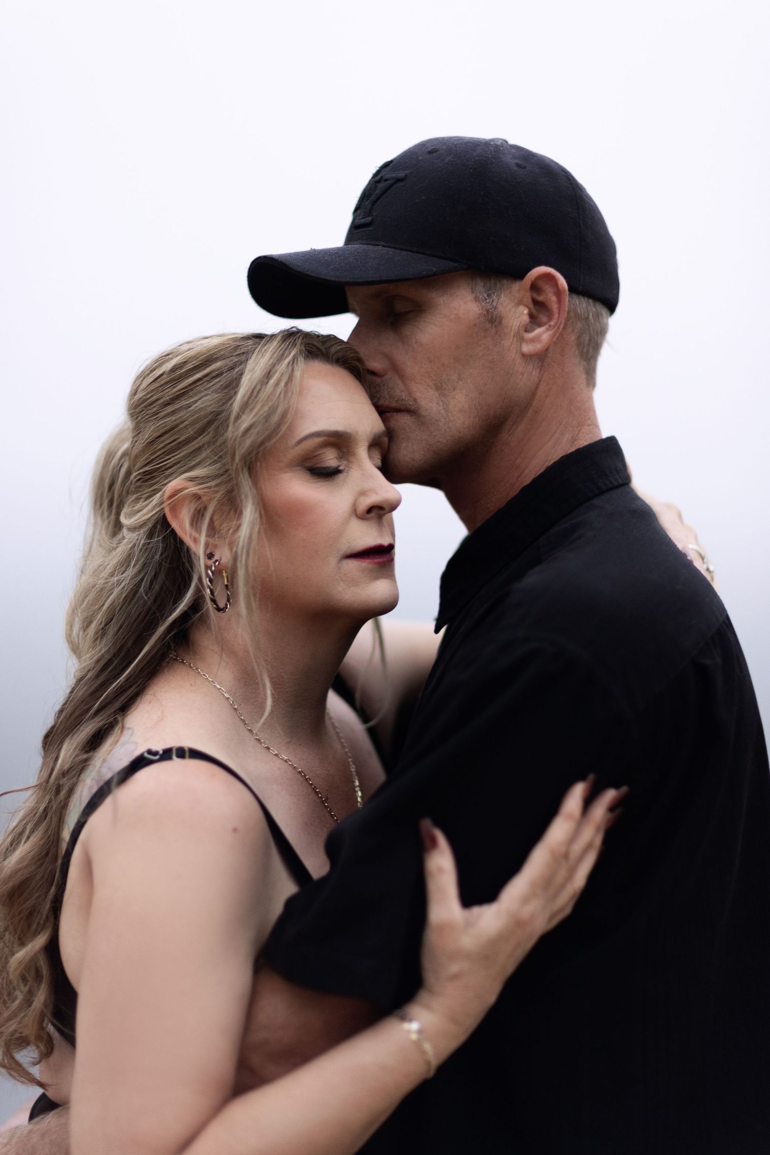 Intimate couple portrait session against moody gray backdrop.