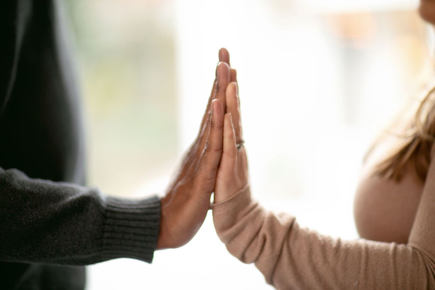 Two pairs of hands meet in a high-five gesture against a white background.