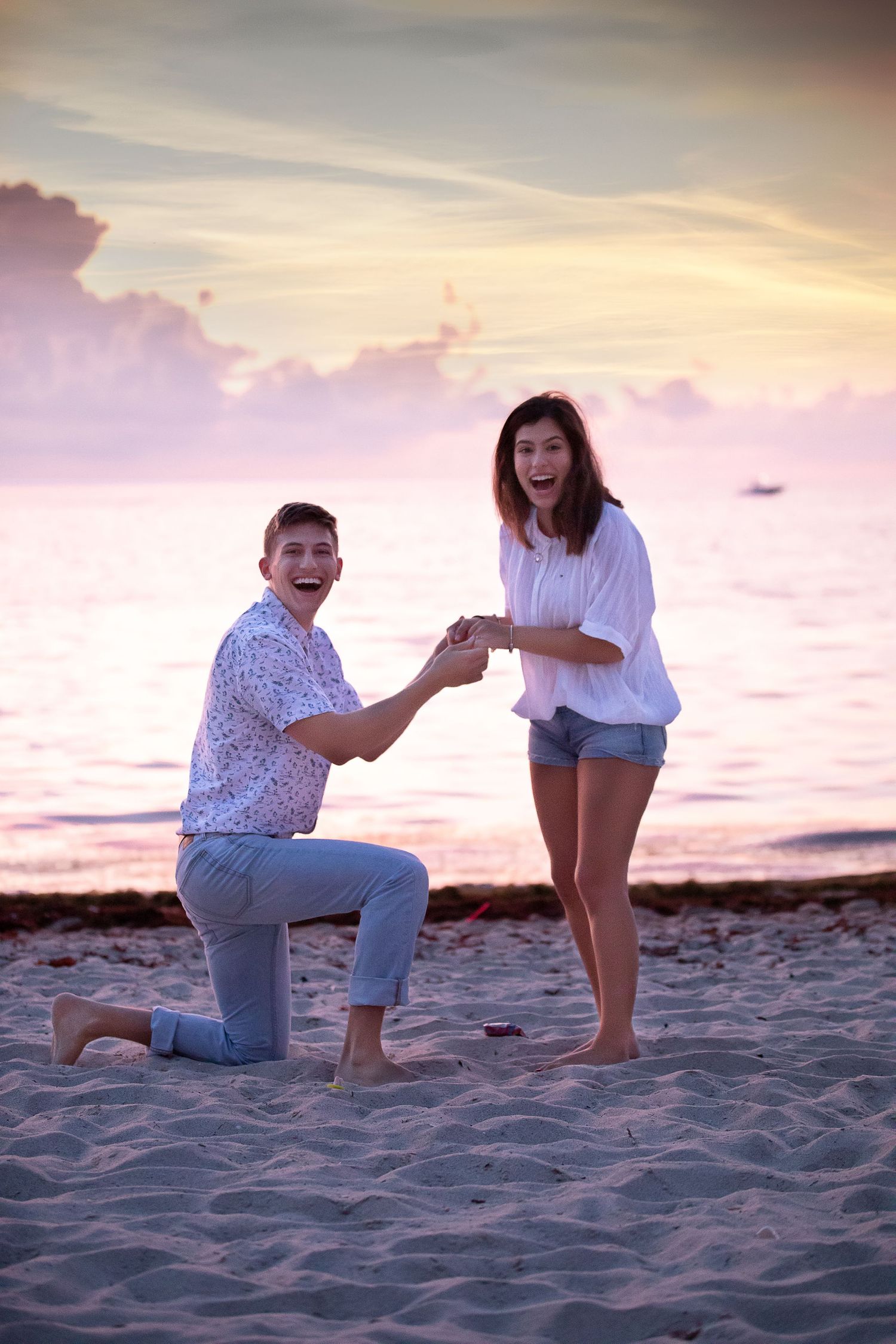 A romantic beach proposal at sunset with a couple on sandy shores.