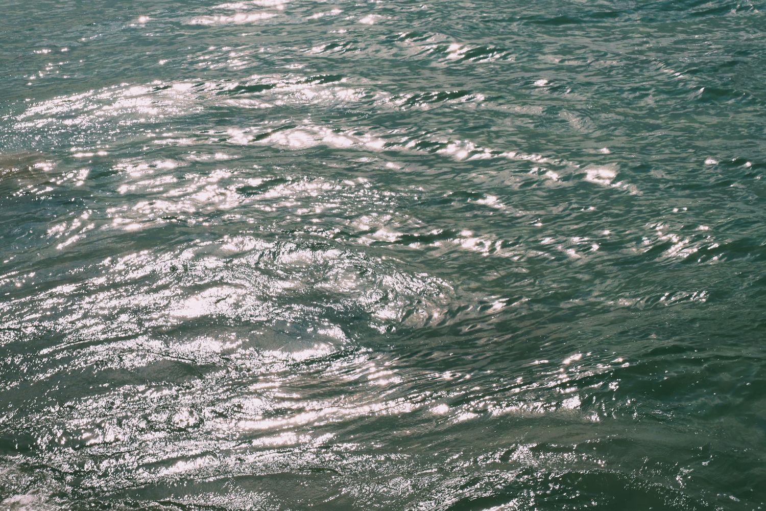 Sunlight reflecting off choppy turquoise ocean waters creating a sparkling effect.
