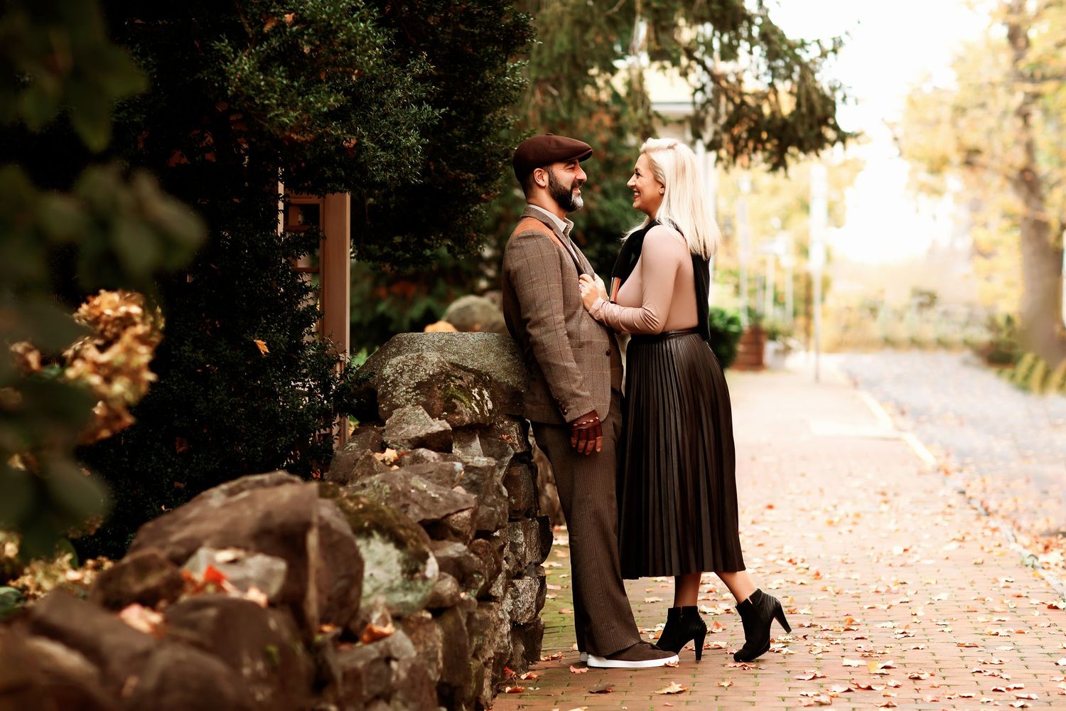 Romantic autumn engagement photos in a park with fallen leaves.