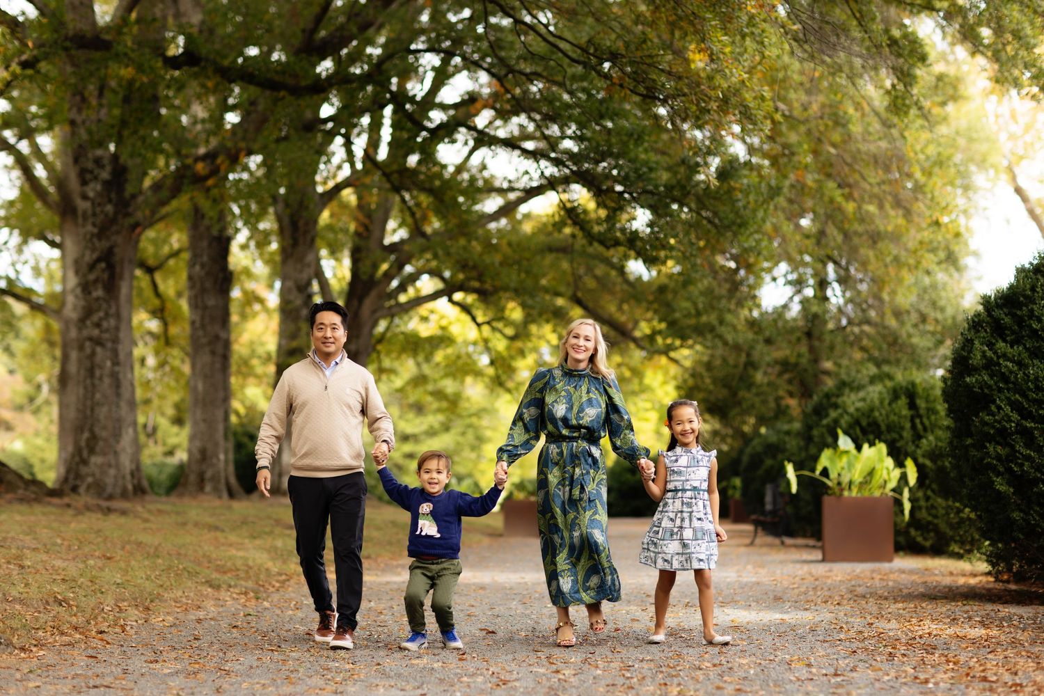 Family walking together on a tree-lined path during autumn.