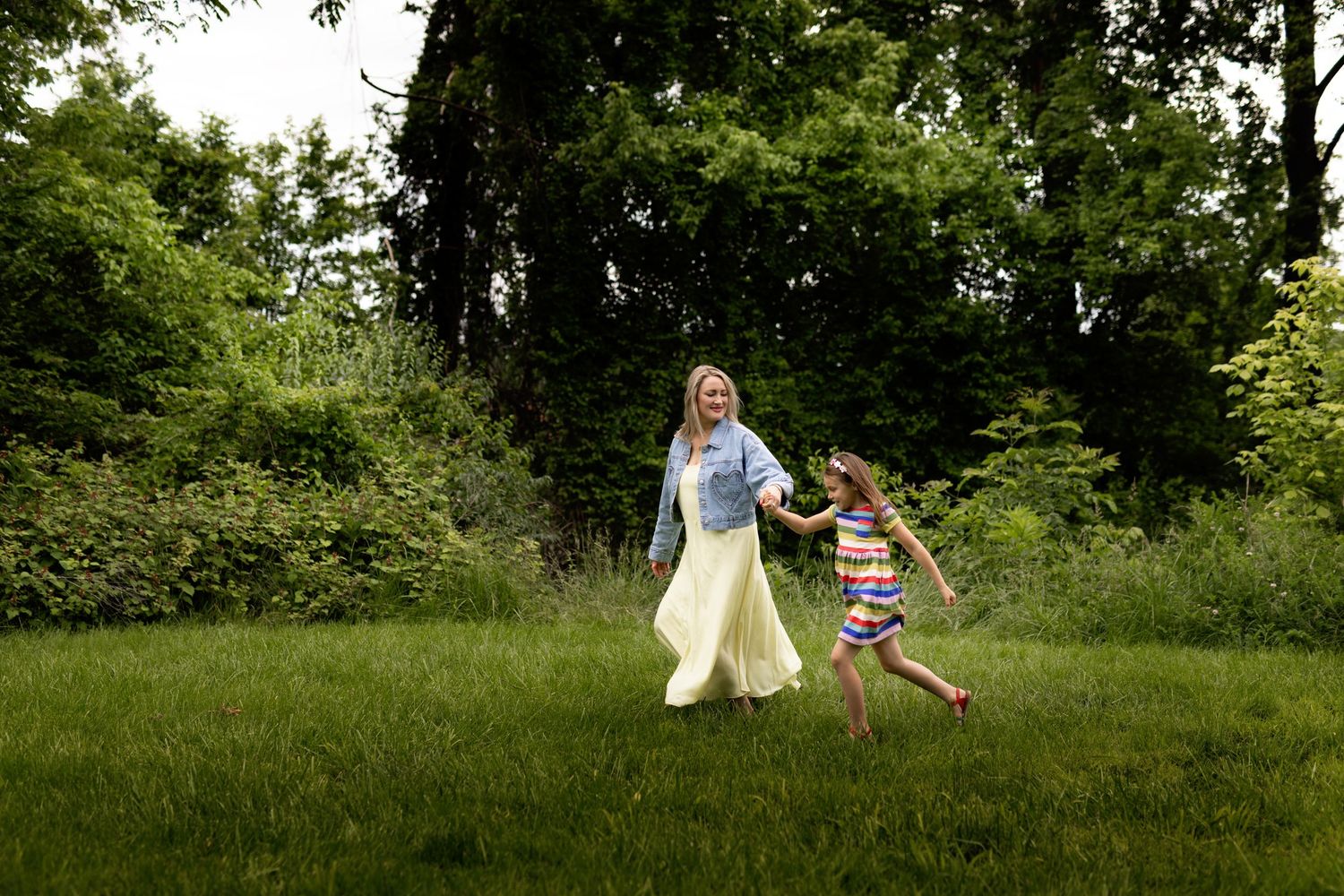 People playing and running through a sunny green field during summer.