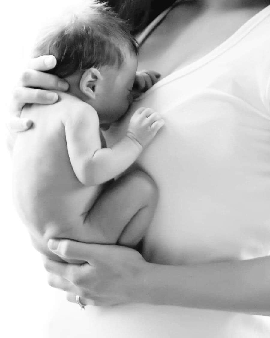 Gentle black and white portrait of newborn being cradled.