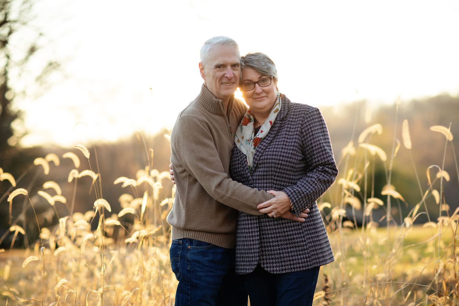 Tender moment captured in golden field during sunset photoshoot.