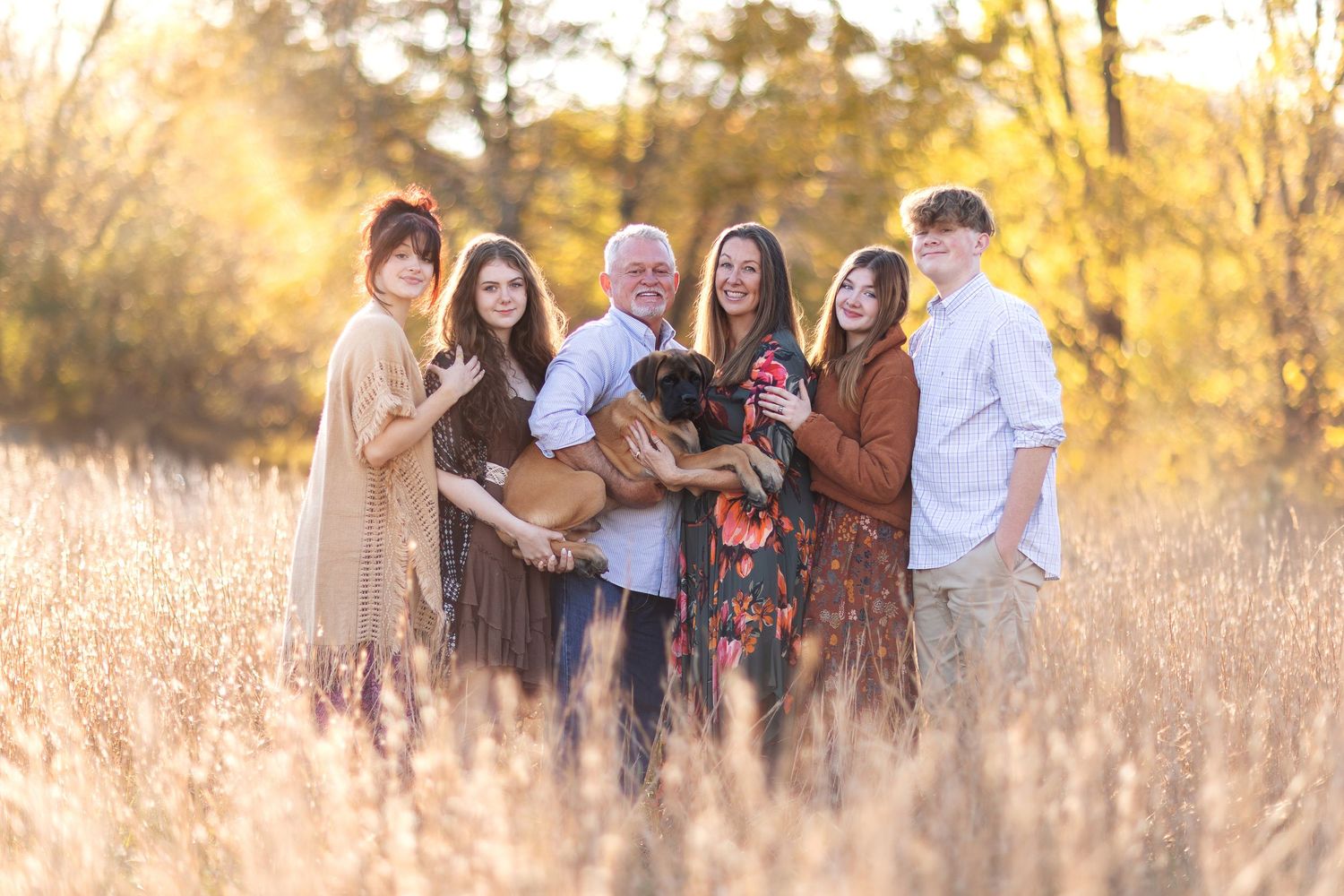 Group enjoying a golden hour photoshoot in a tall grass field at sunset.