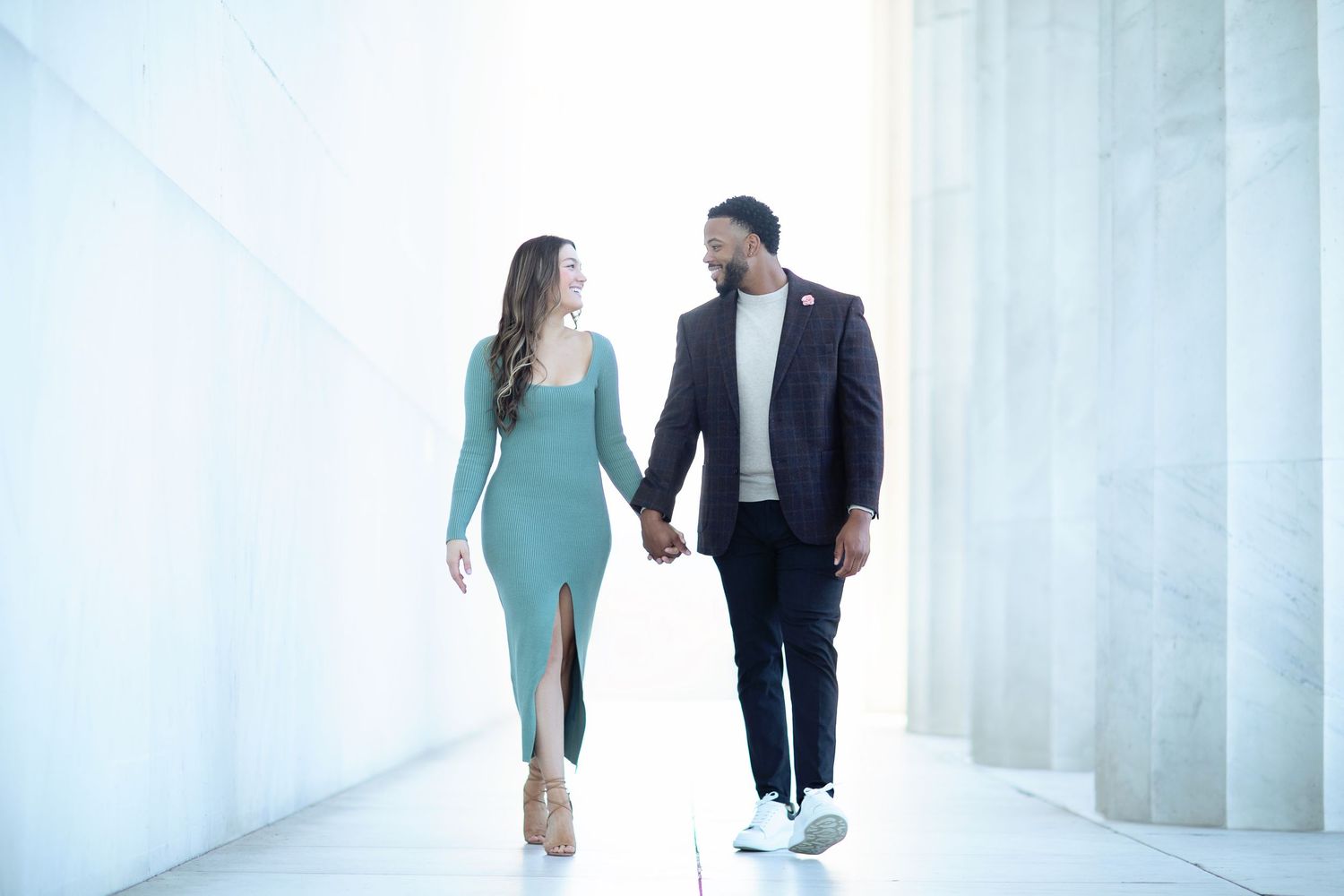 Romantic couple walking through a bright white modern hallway.