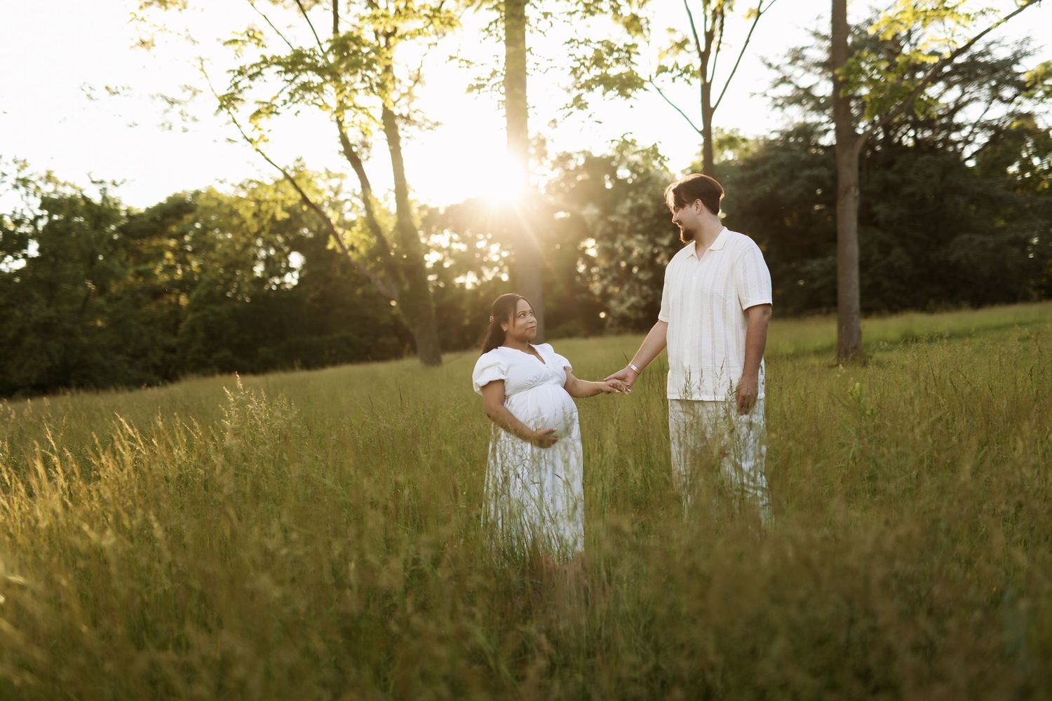 Golden hour maternity photography session in a sunlit meadow.