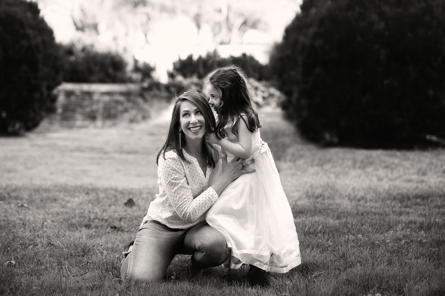 Black and white portrait of tender bonding moment in a grassy field on a sunny day.