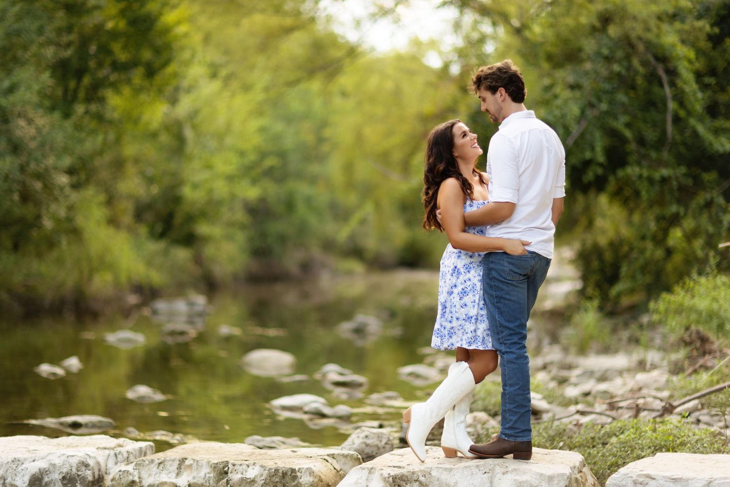 Family group poses together on rocky riverbank in casual outdoor setting.