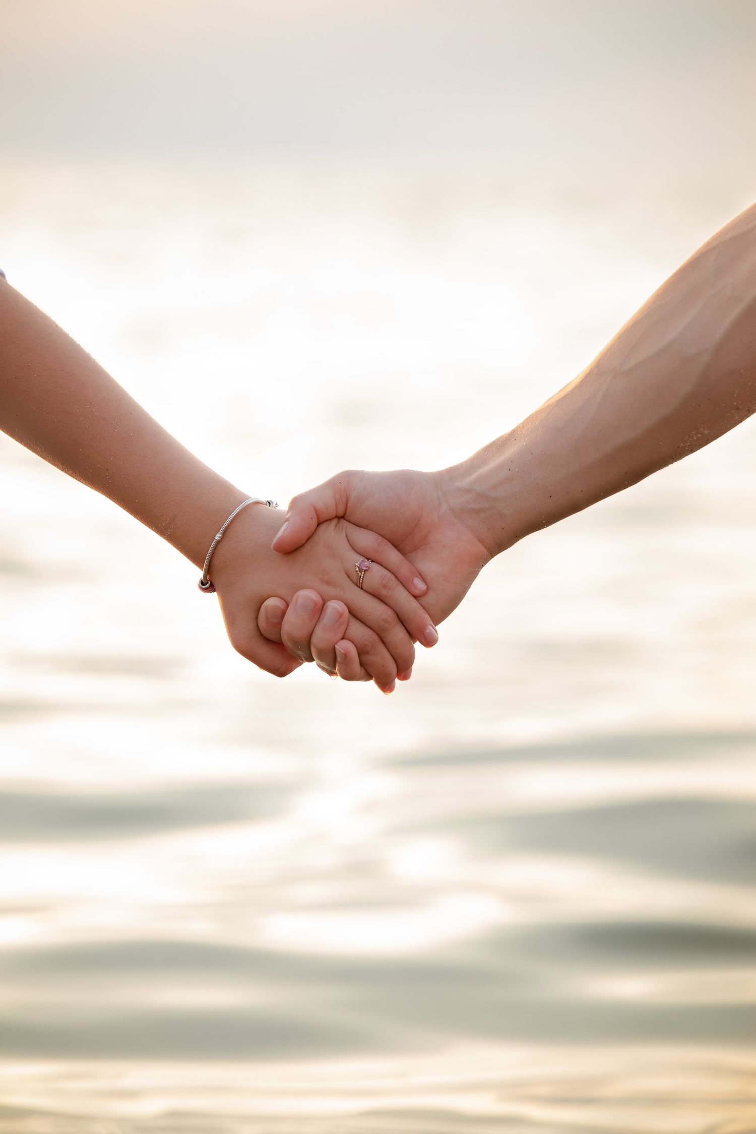 Close-up shots of hands holding each other against a sunset sky background.