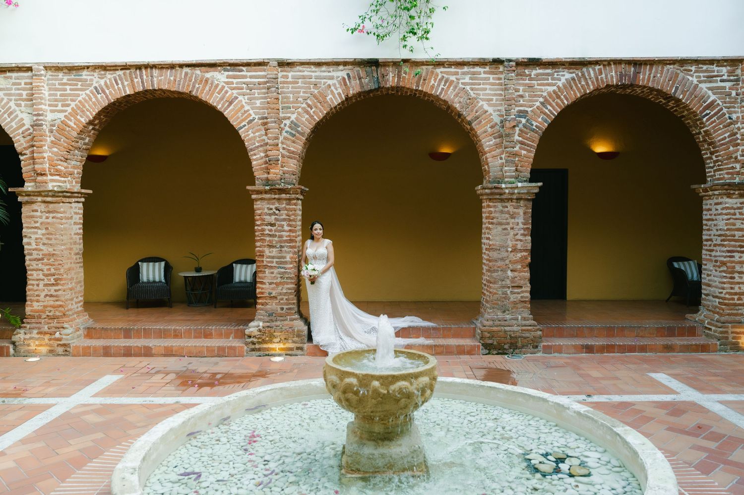 Stone archways and columns surround a tranquil courtyard fountain in a historic Mediterranean-style building.