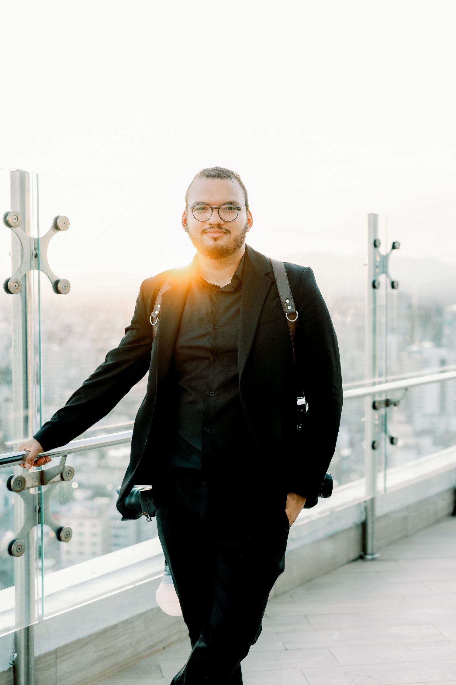 Person in dark suit posing confidently on modern architectural terrace.