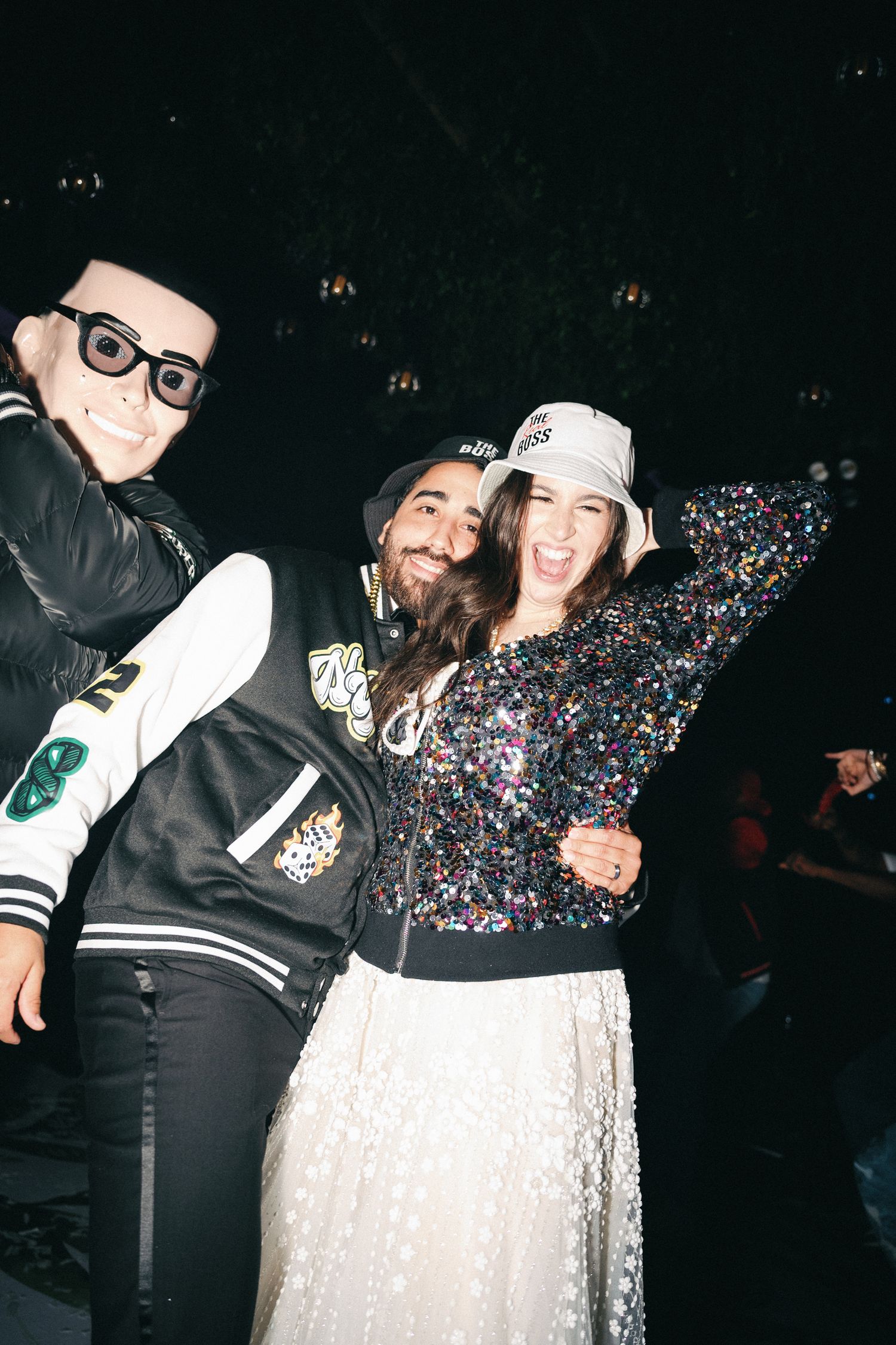 Group of friends posing together at a nighttime party wearing casual and sparkly outfits.