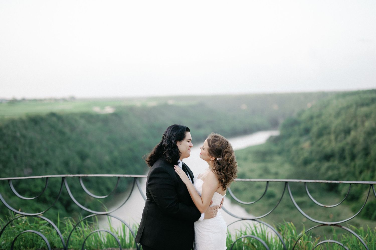 A couple shares an intimate kiss in front of a misty mountain landscape during their wedding photoshoot.