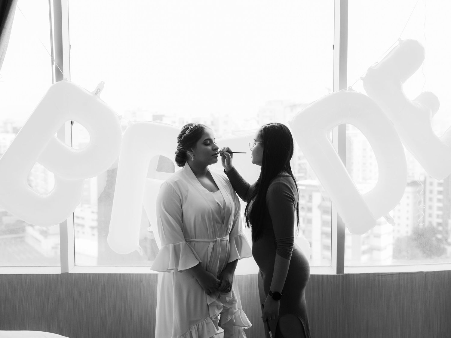 Black and white wedding photos showing silhouettes of a couple sharing intimate moments by a window.