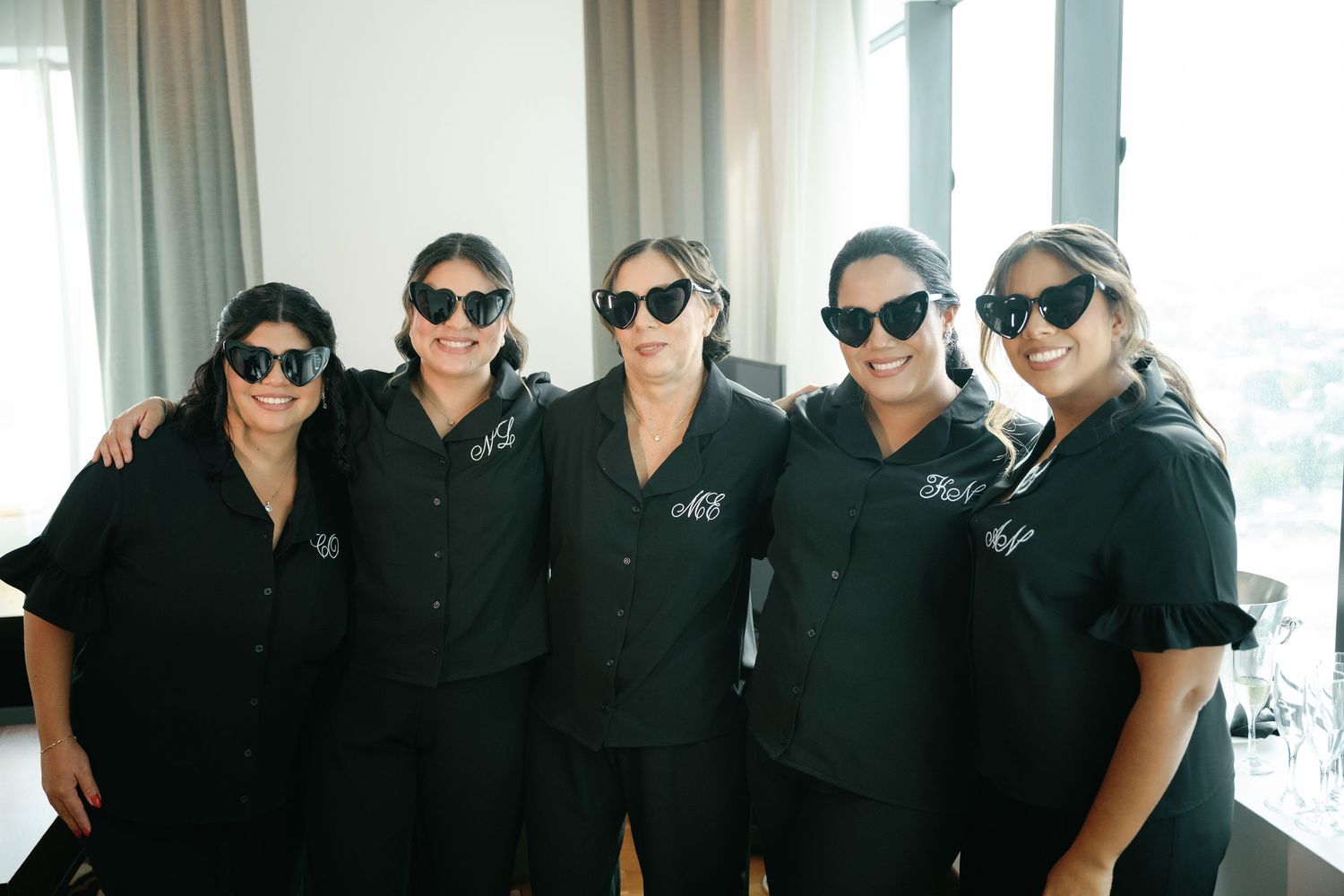 A group of people wearing matching black shirts and sunglasses pose together in a casual lineup.
