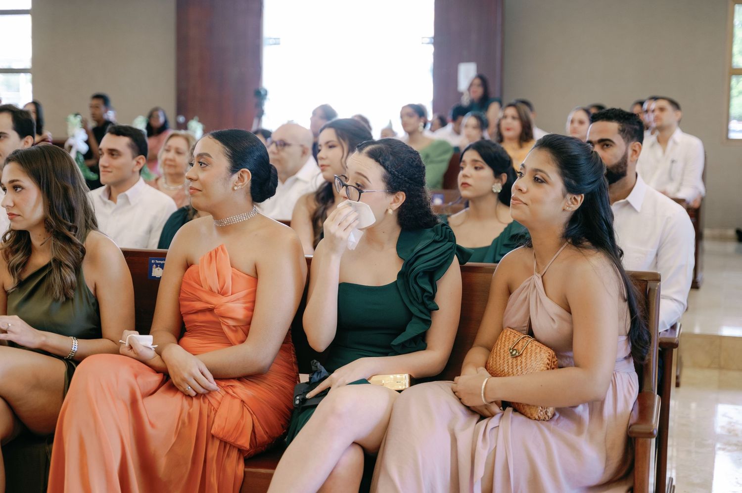 Wedding guests seated in rows show emotional reactions during a ceremony.