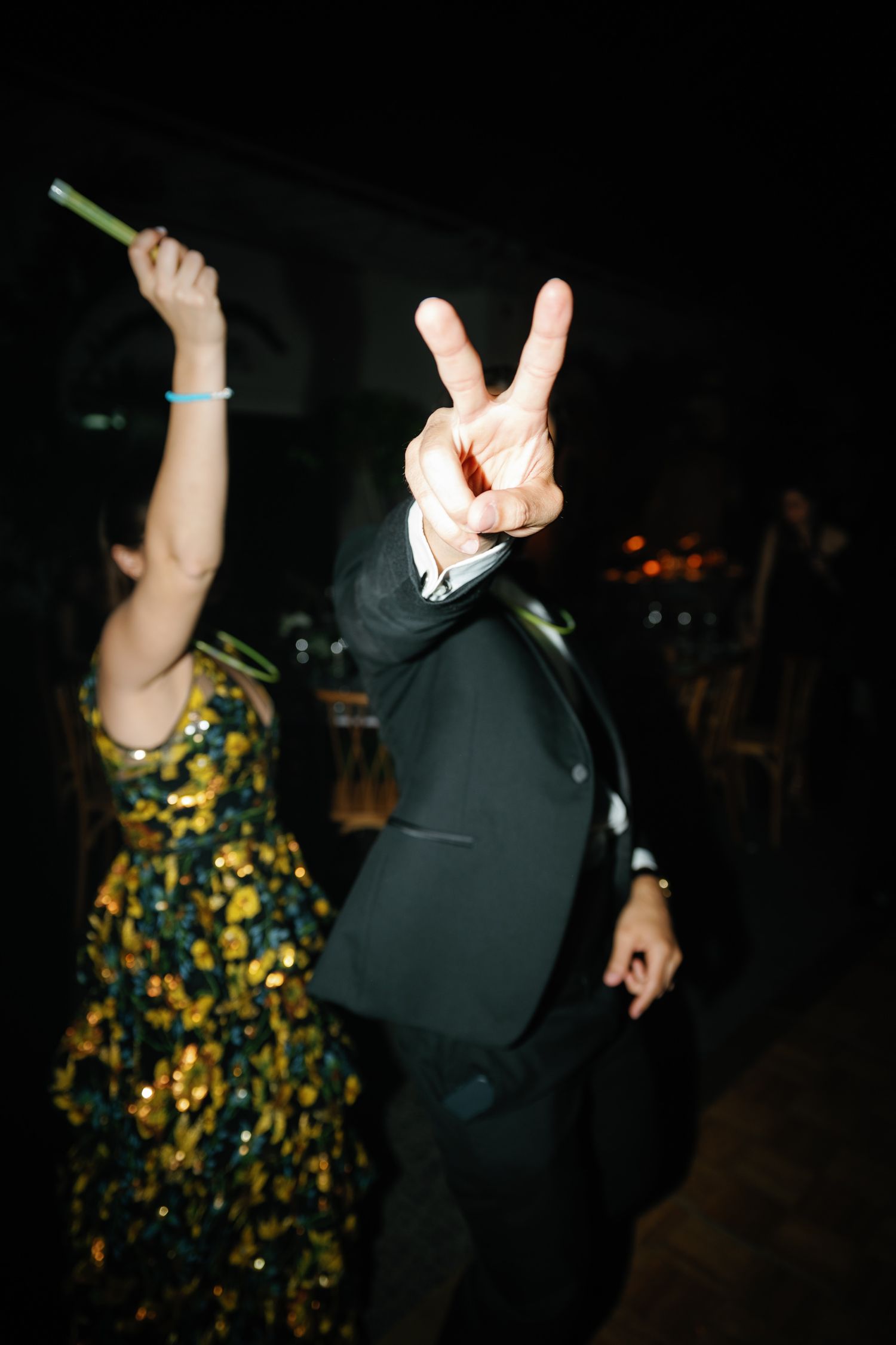 Party guests dance with raised hands in a dimly lit venue, creating a lively celebration atmosphere.