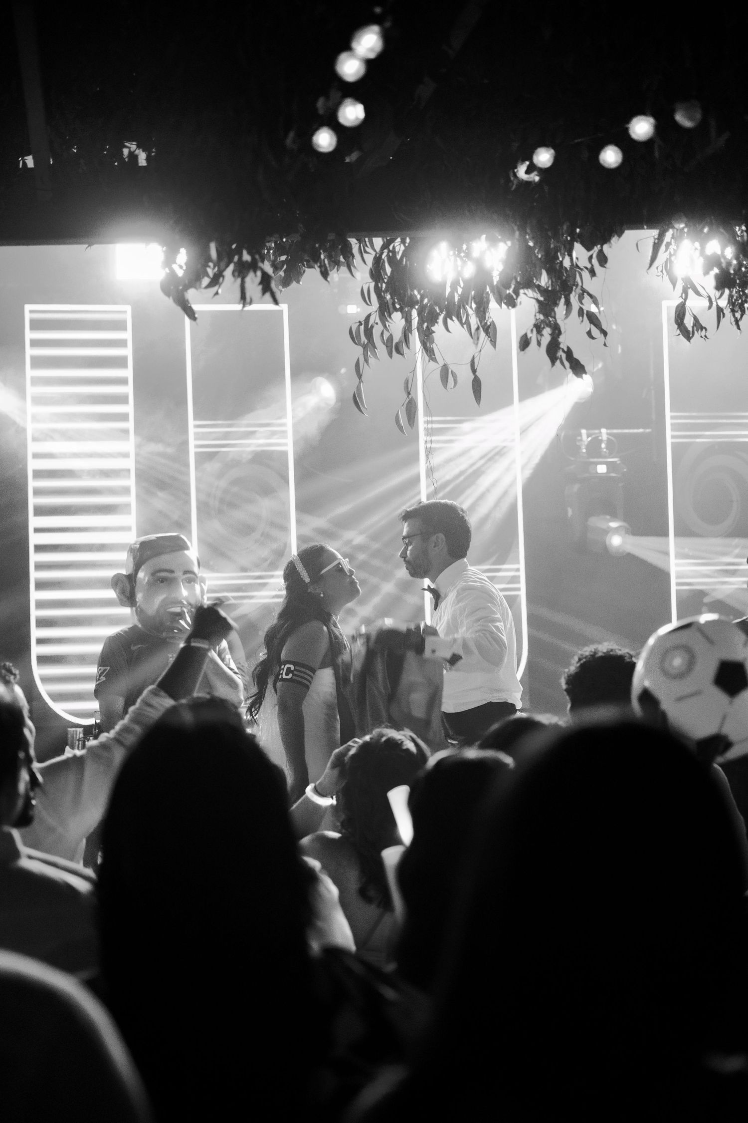 Black and white photo of nightclub scene with bright stage lights and geometric backdrop.