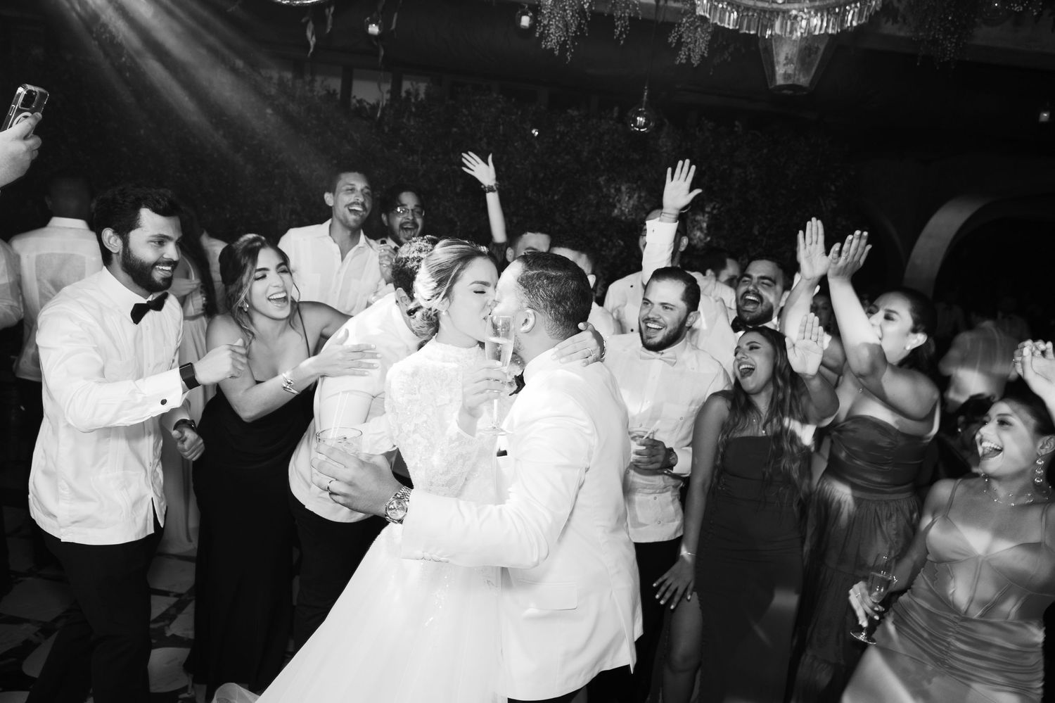 Black and white photos of wedding guests dancing and celebrating on a crowded dance floor.