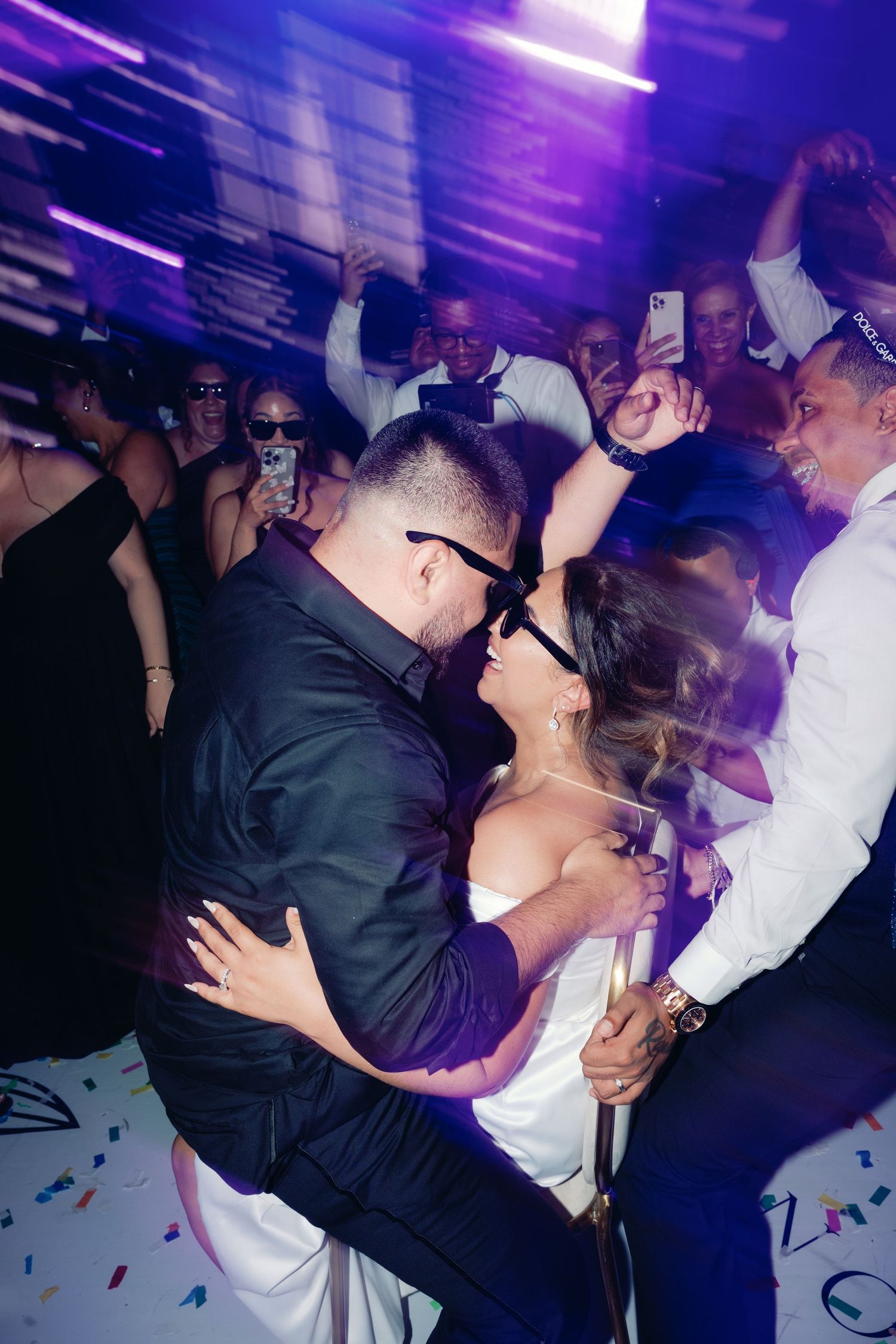 Wedding couple dips and dances under purple lighting at their reception celebration.