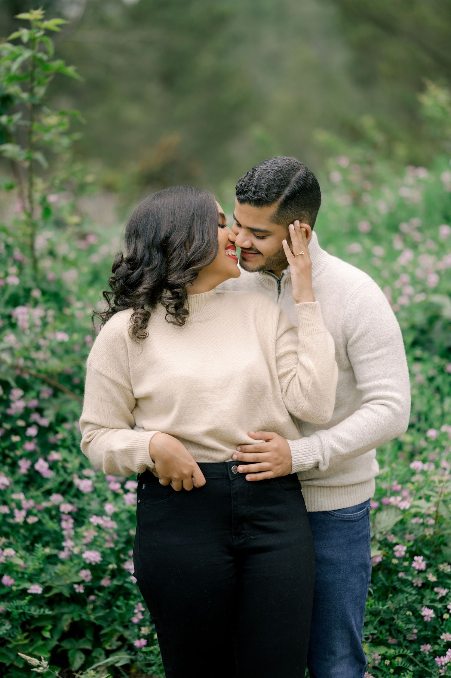 A couple shares tender moments together while standing in a blooming wildflower field during a romantic photoshoot.