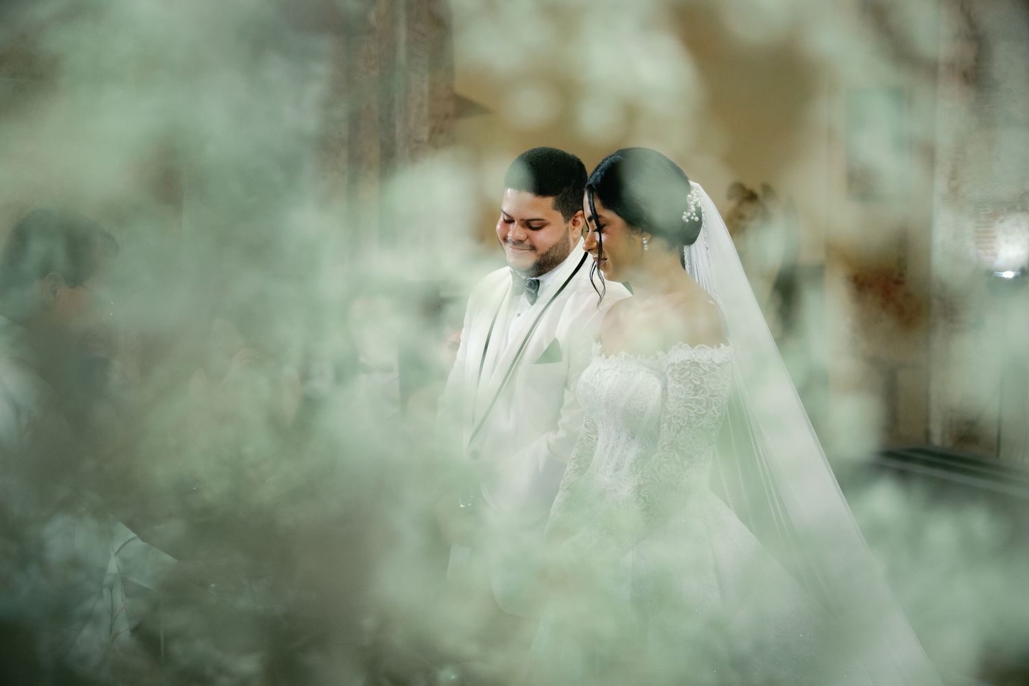 A romantic wedding couple embraces in an ethereal setting with soft natural light and fog effects.