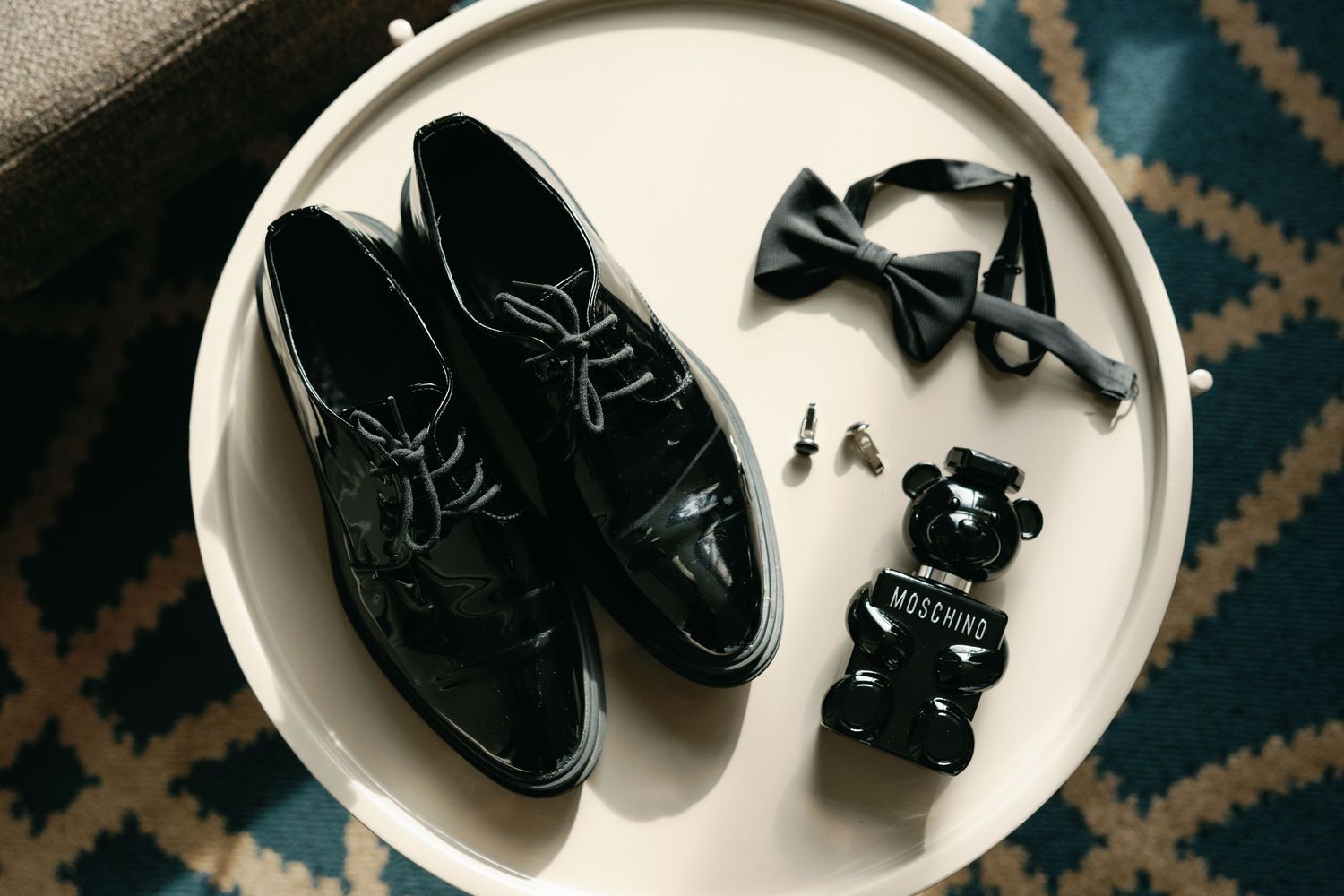 A series of black leather baby shoes arranged in a sequence showing different angles on a white plate.