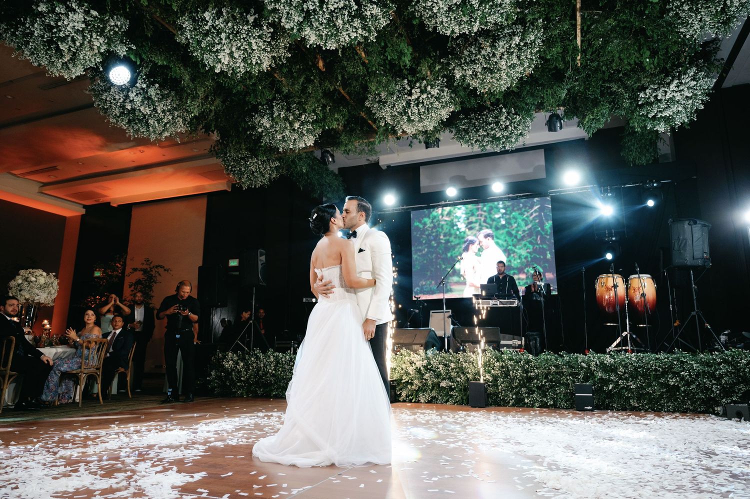 Romantic outdoor wedding reception at night with twinkling lights and dancing under trees.