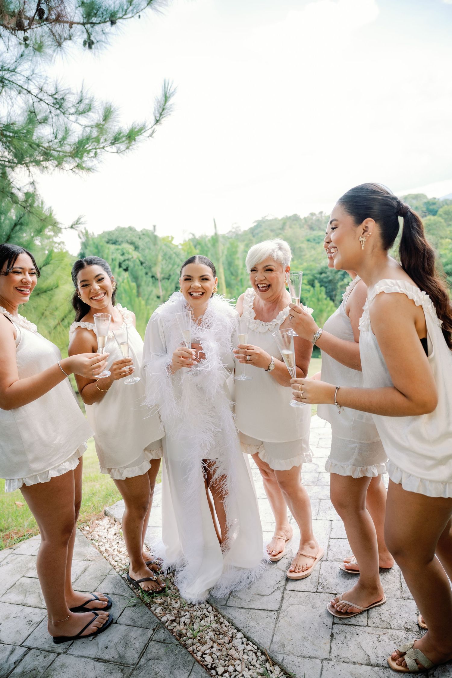 A group in white outfits poses playfully in a sequence of candid shots outdoors against a natural backdrop.
