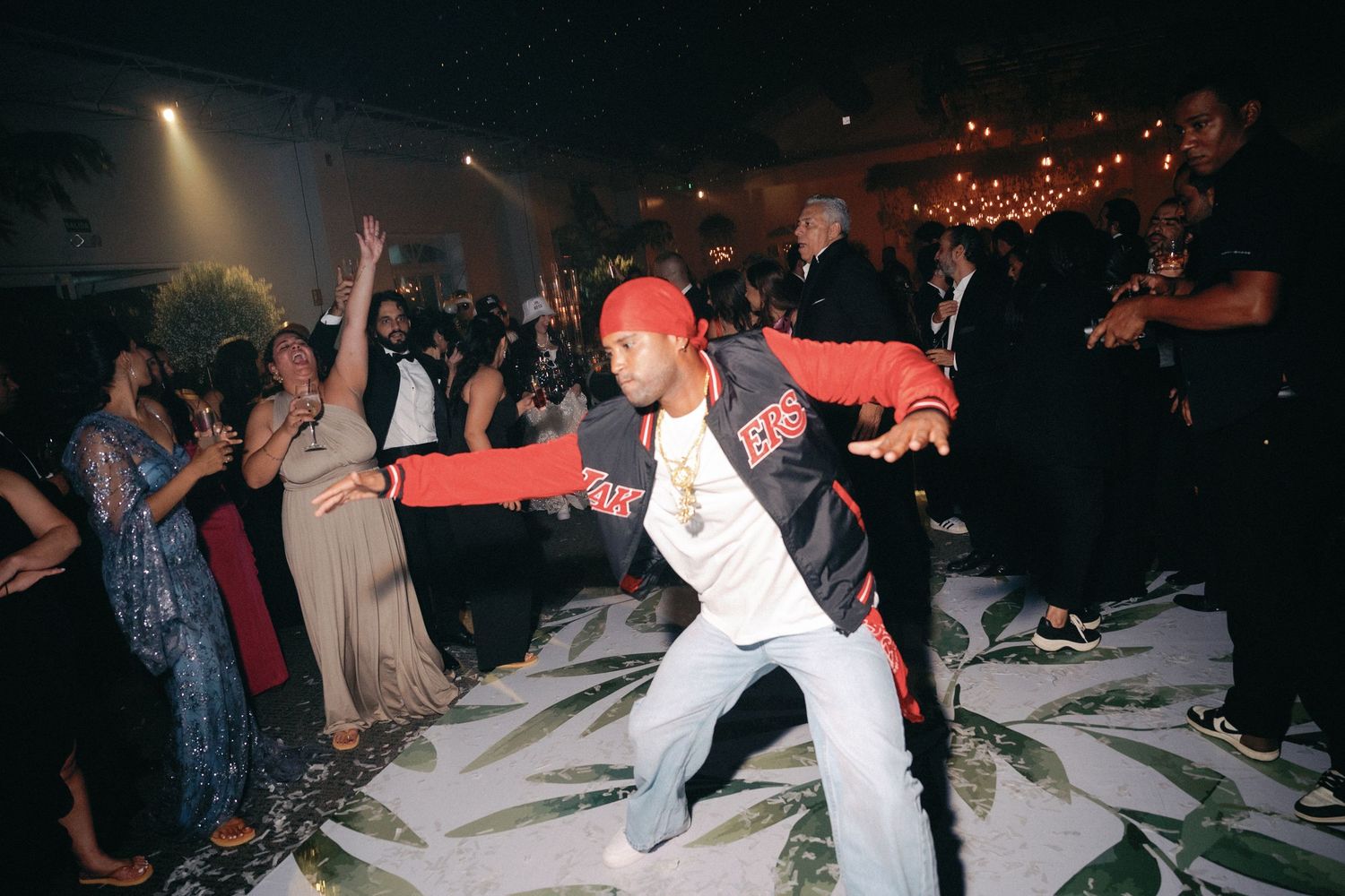 Person in white shirt and red cap performs dramatic dance moves on a confetti-covered floor.