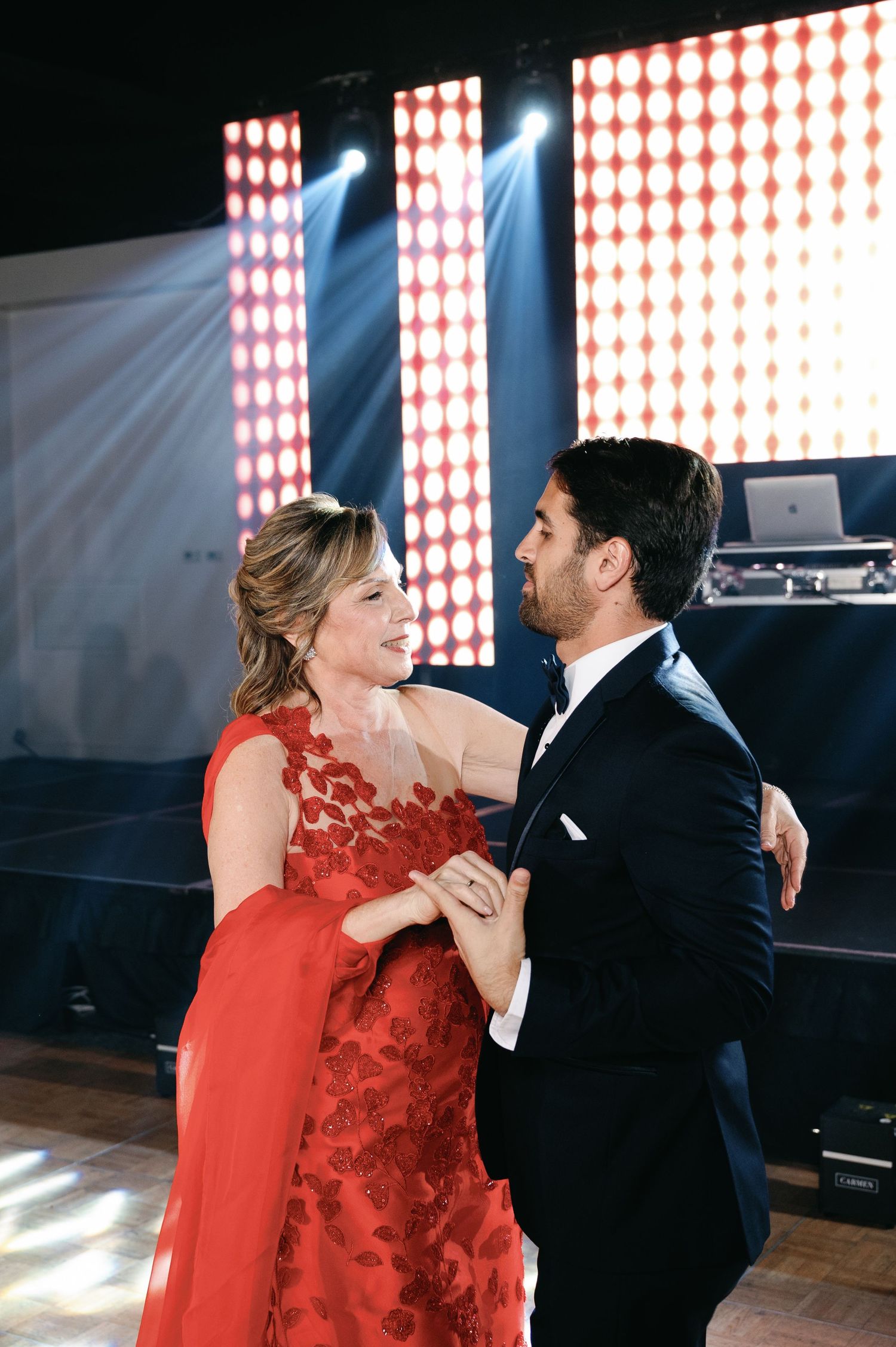 A couple dances together at a reception, with the woman wearing a stunning red lace dress.