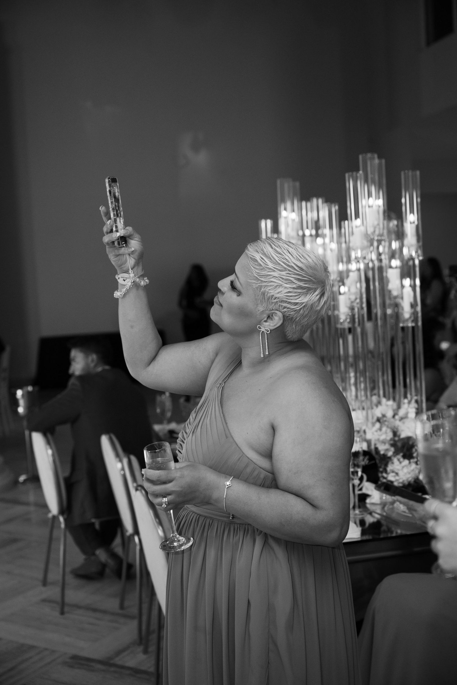 Wedding guests enjoying reception celebration in dimly lit venue with elegant table settings.