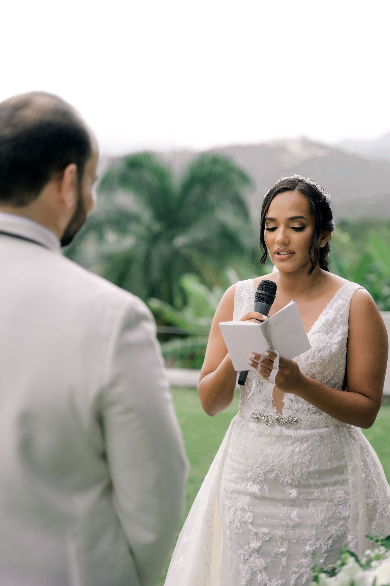 A couple exchanges emotional vows during an outdoor wedding ceremony surrounded by lush tropical greenery.