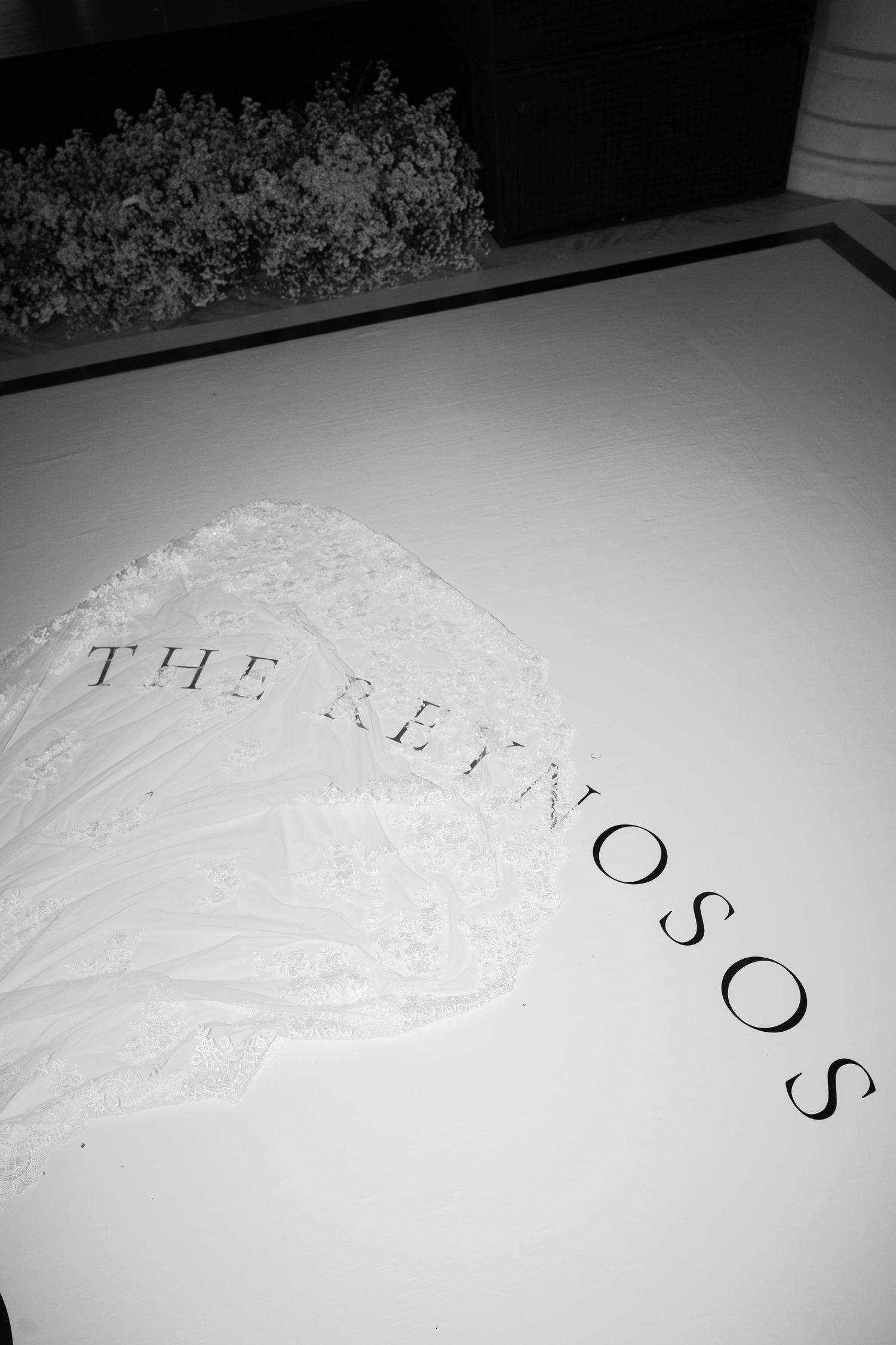 White lace or textured pattern on light background with partial text visible.
