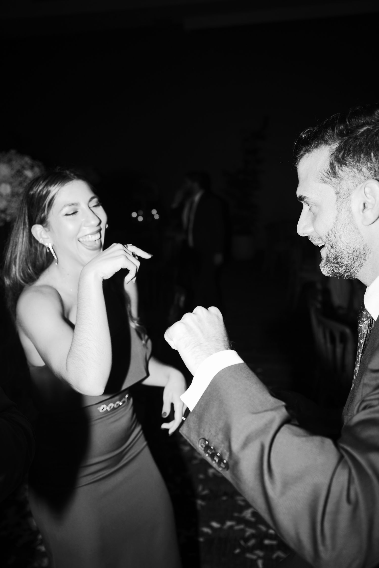 Black and white candid shots of guests dancing and celebrating at a nighttime wedding reception.
