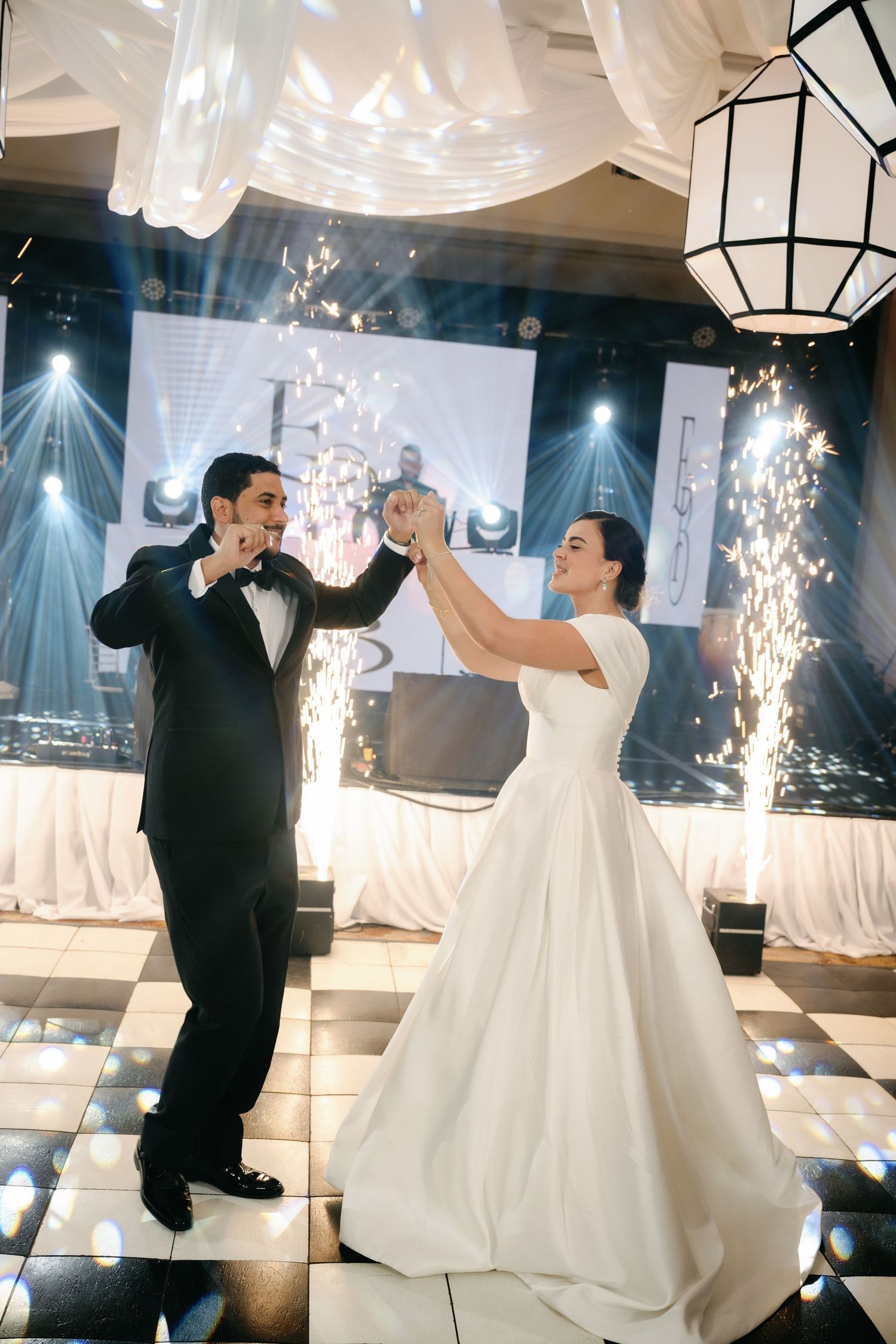 A bride and groom dance together on an illuminated dance floor with sparklers creating a magical atmosphere at their wedding.