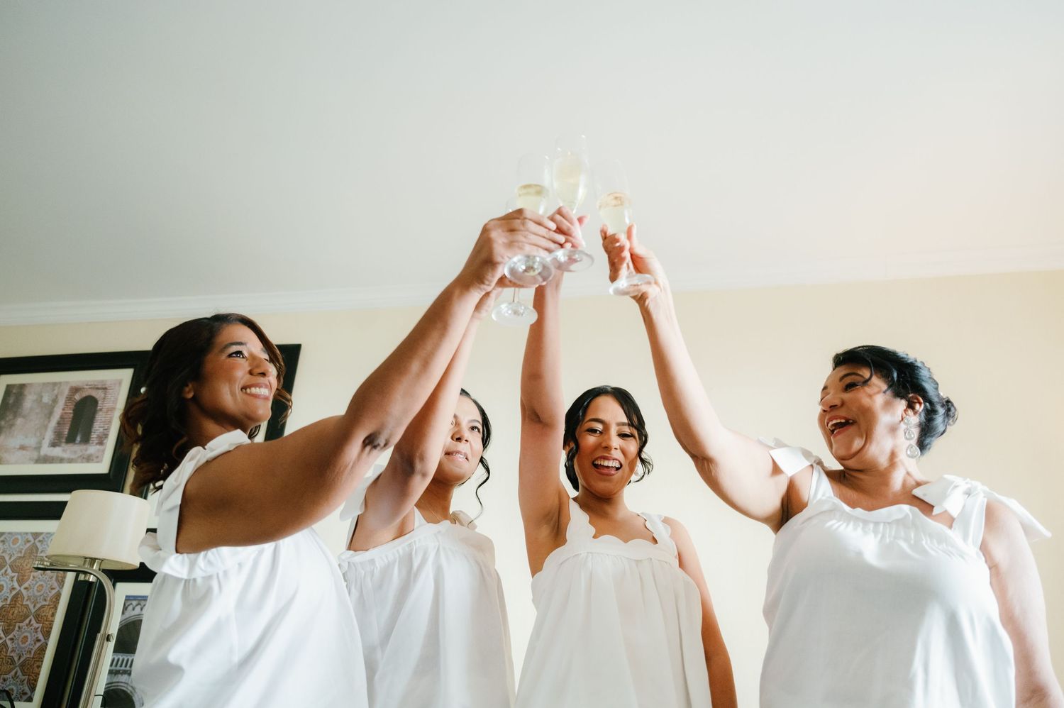 A group of people in white outfits raise their hands together in celebration during a joyful moment.