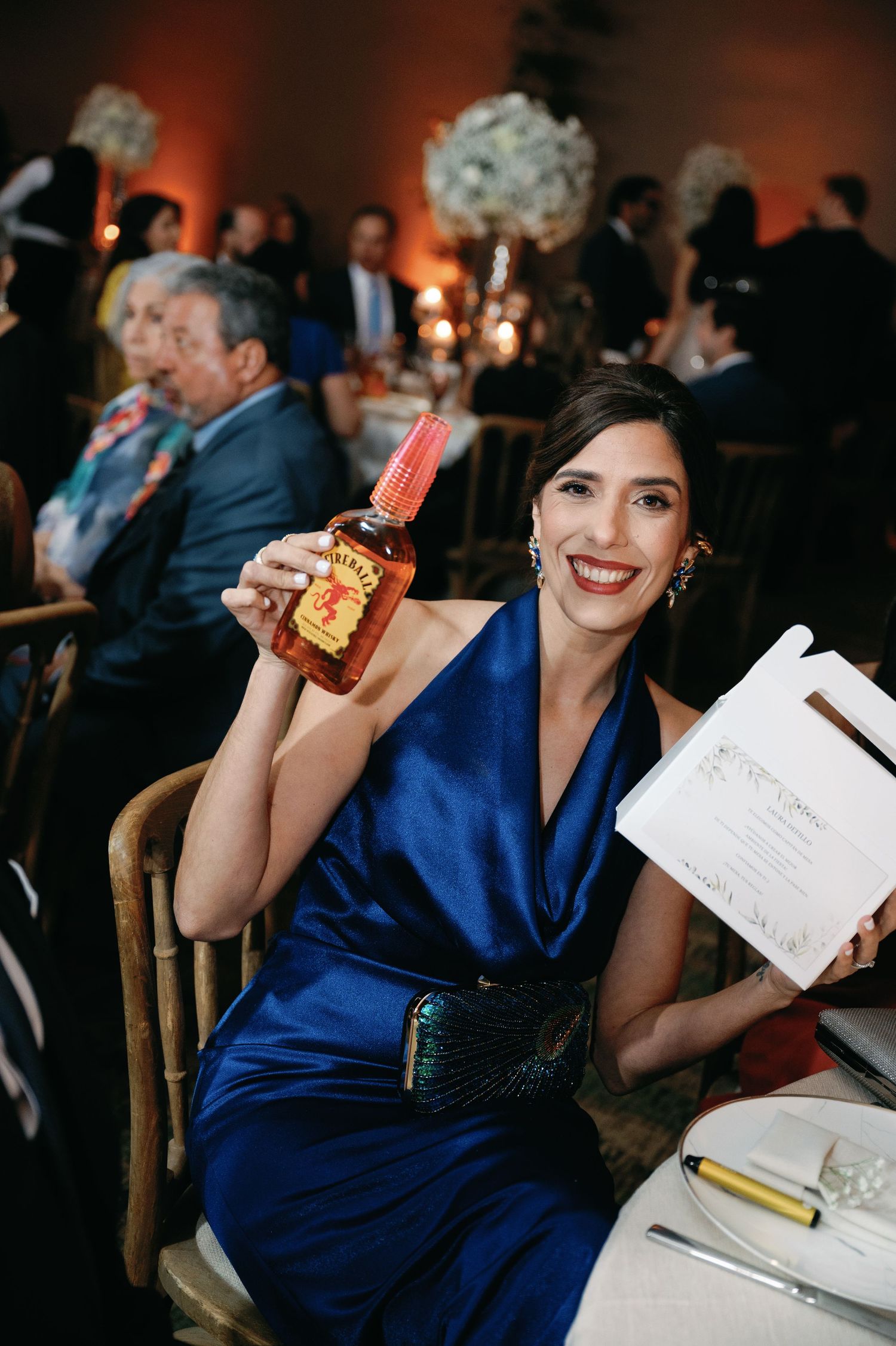 Wedding guest in a royal blue dress takes notes during the reception celebration.