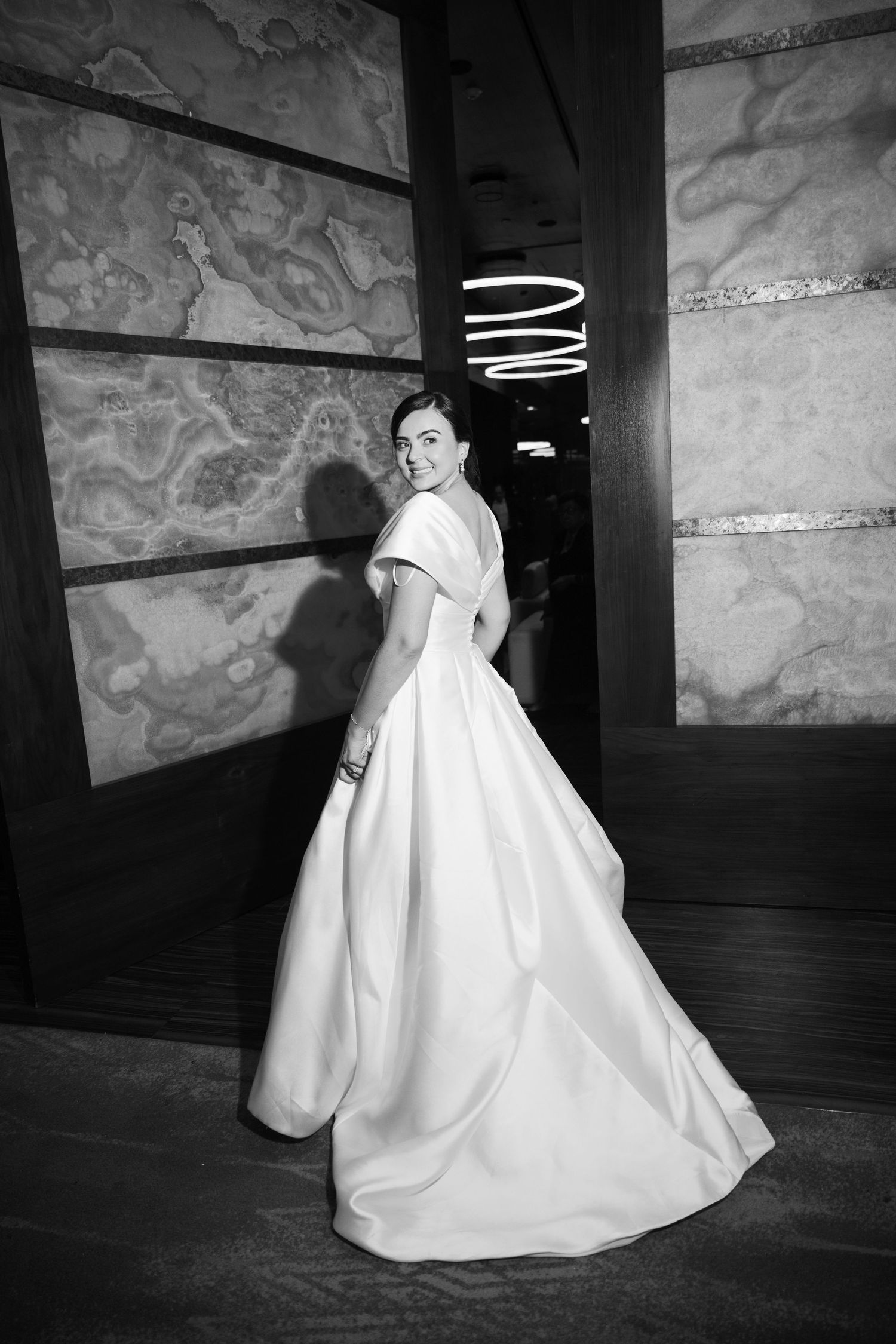 A dramatic black and white photo series showing a flowing white ballgown in an elegant dark interior space.