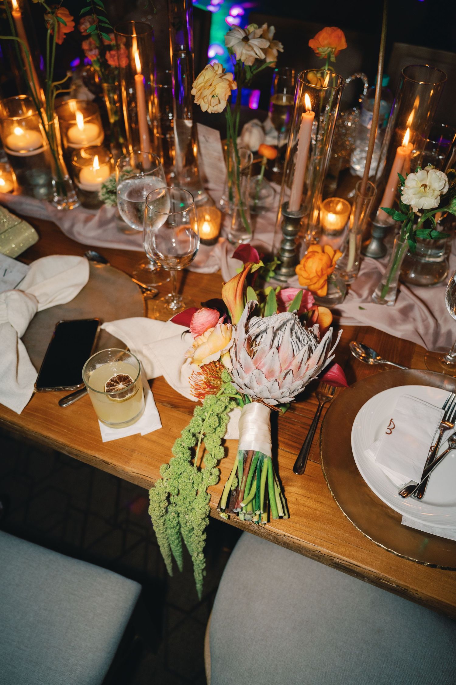 Elegant table setting with candlelight, colorful flowers, and place settings at a wedding reception.