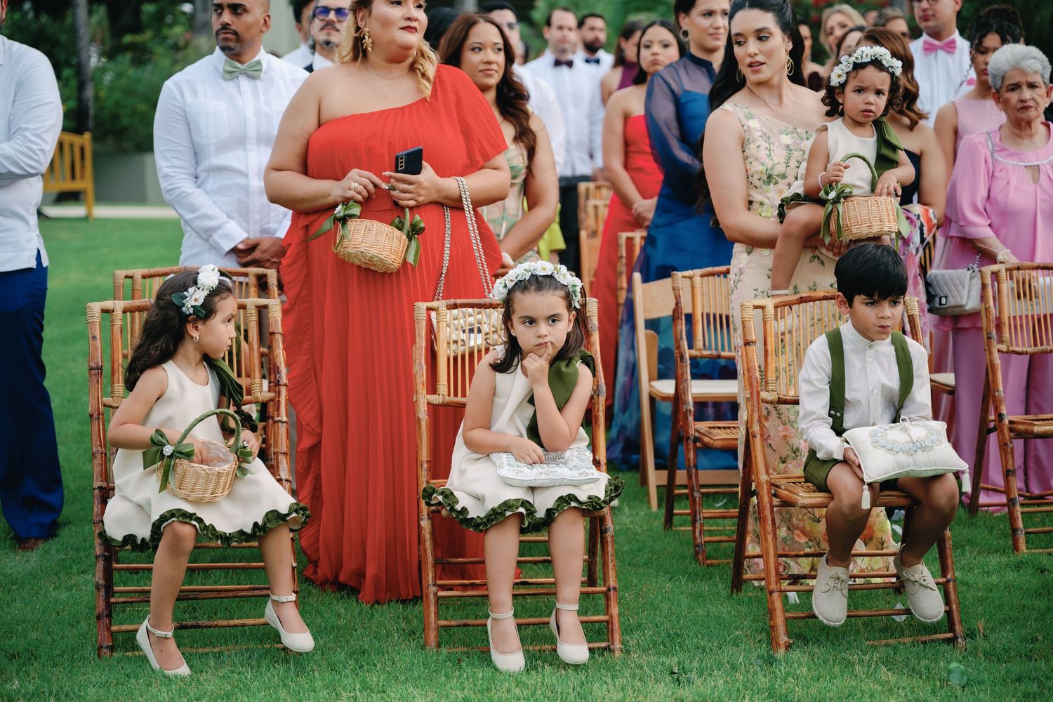 Outdoor wedding ceremony guests seated in rows of wooden chairs on a grassy lawn.